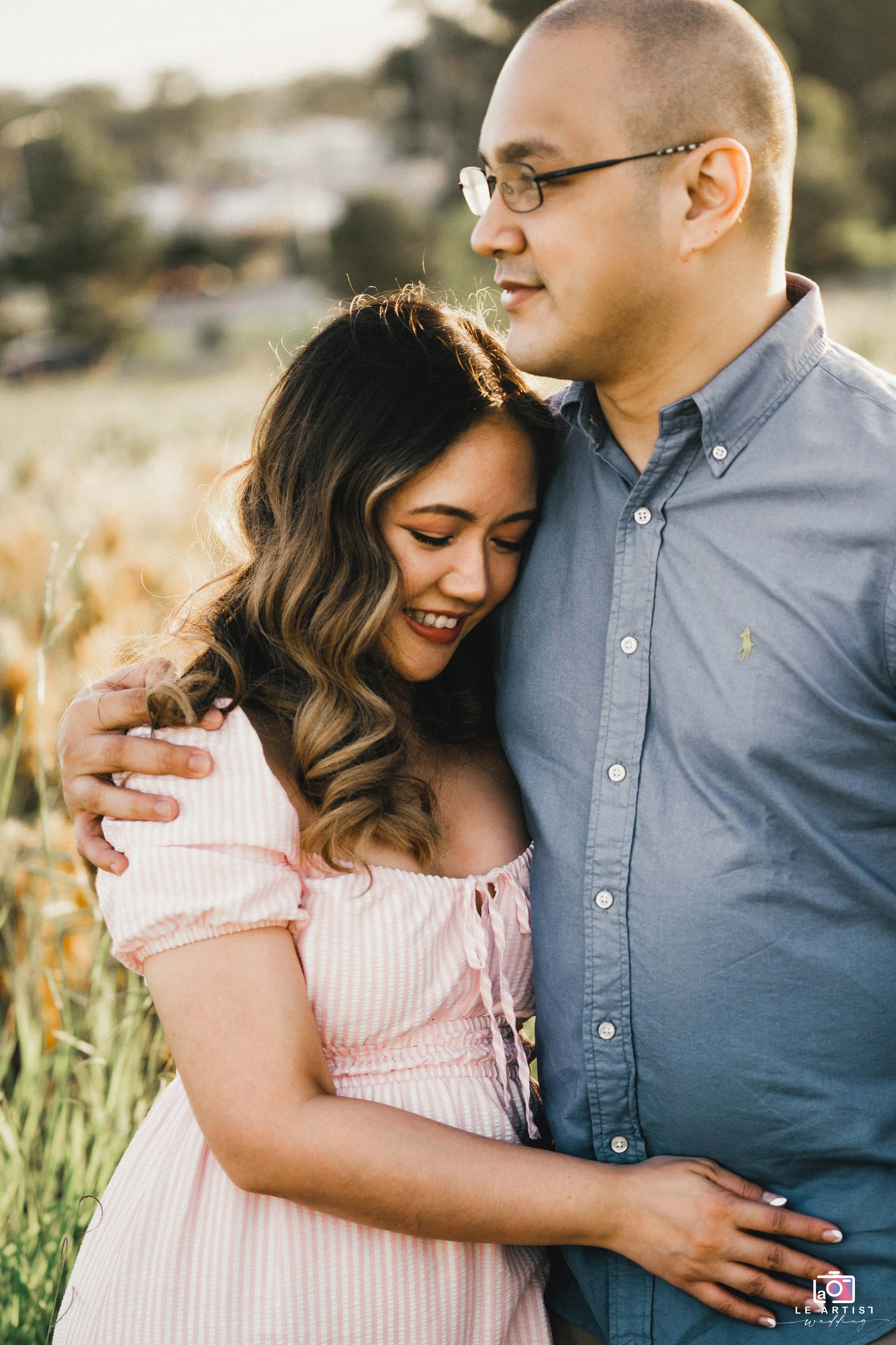 The couple shares a tender moment, embracing each other amidst a serene outdoor setting, symbolizing their love and closeness. Le Artist Wedding