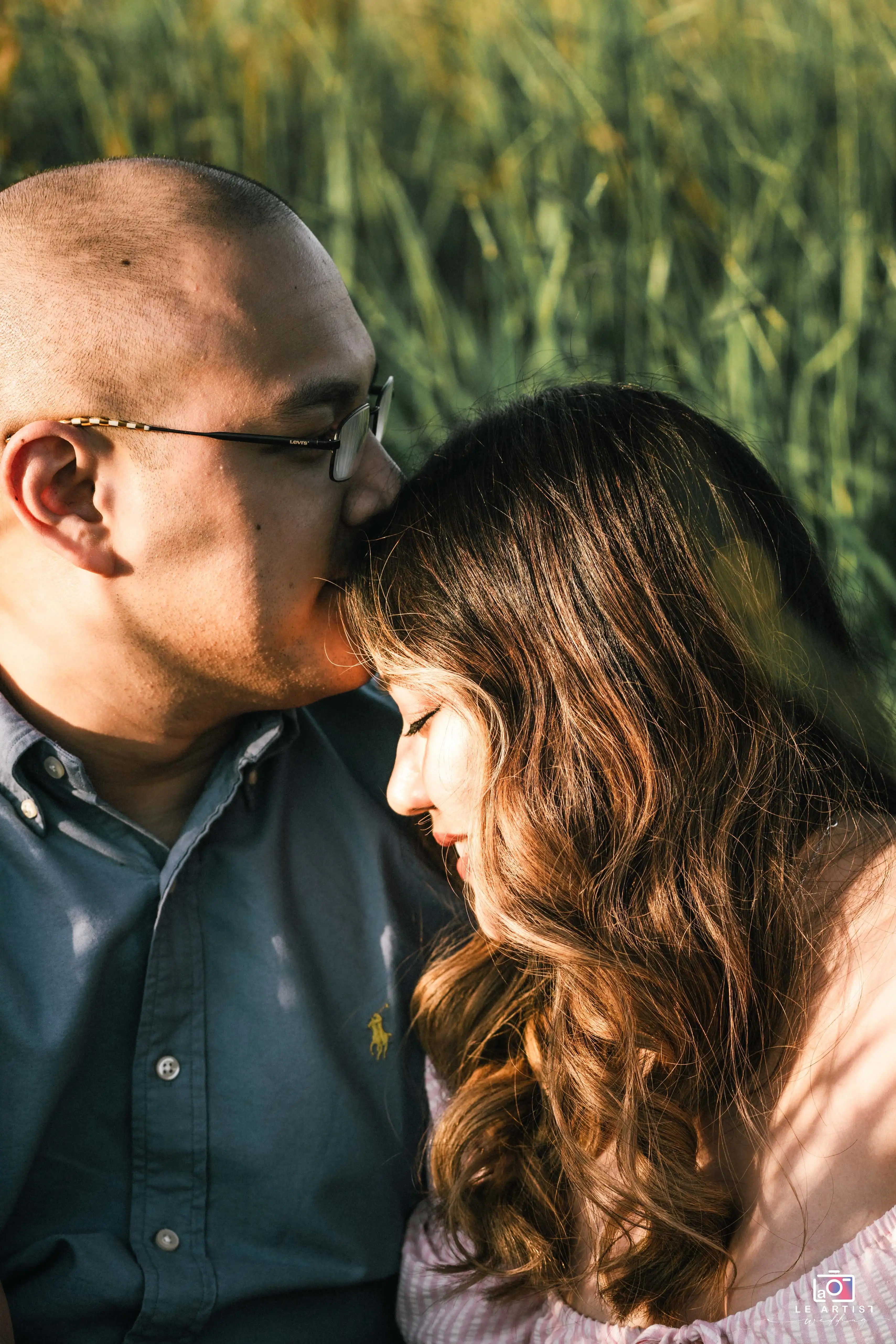 A tender moment captured between a couple, as they share an intimate embrace amidst a natural backdrop, highlighting their deep connection. Le Artist Wedding