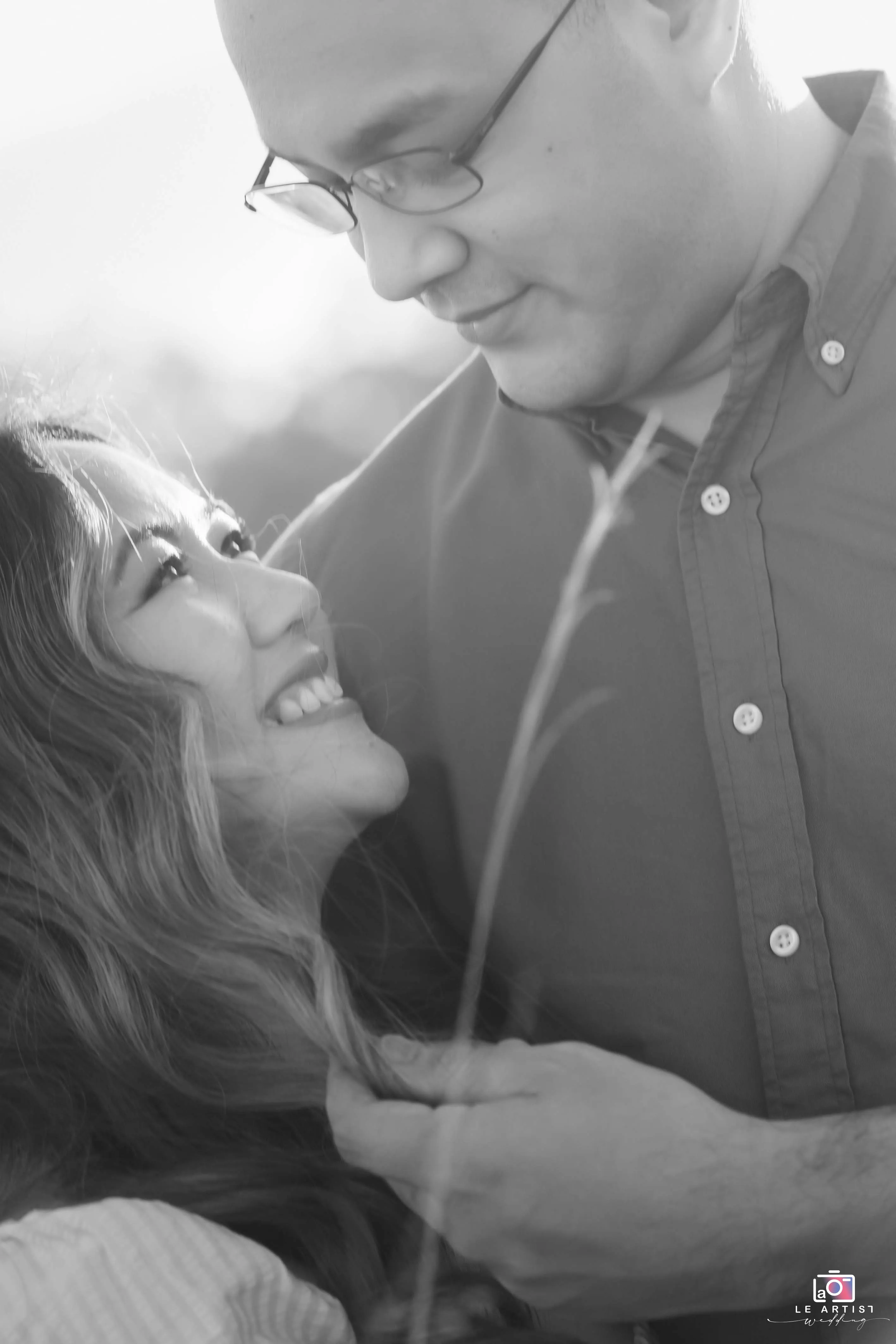 A heartwarming black and white moment capturing the couple's joyful gaze into each other's eyes. Le Artist Wedding