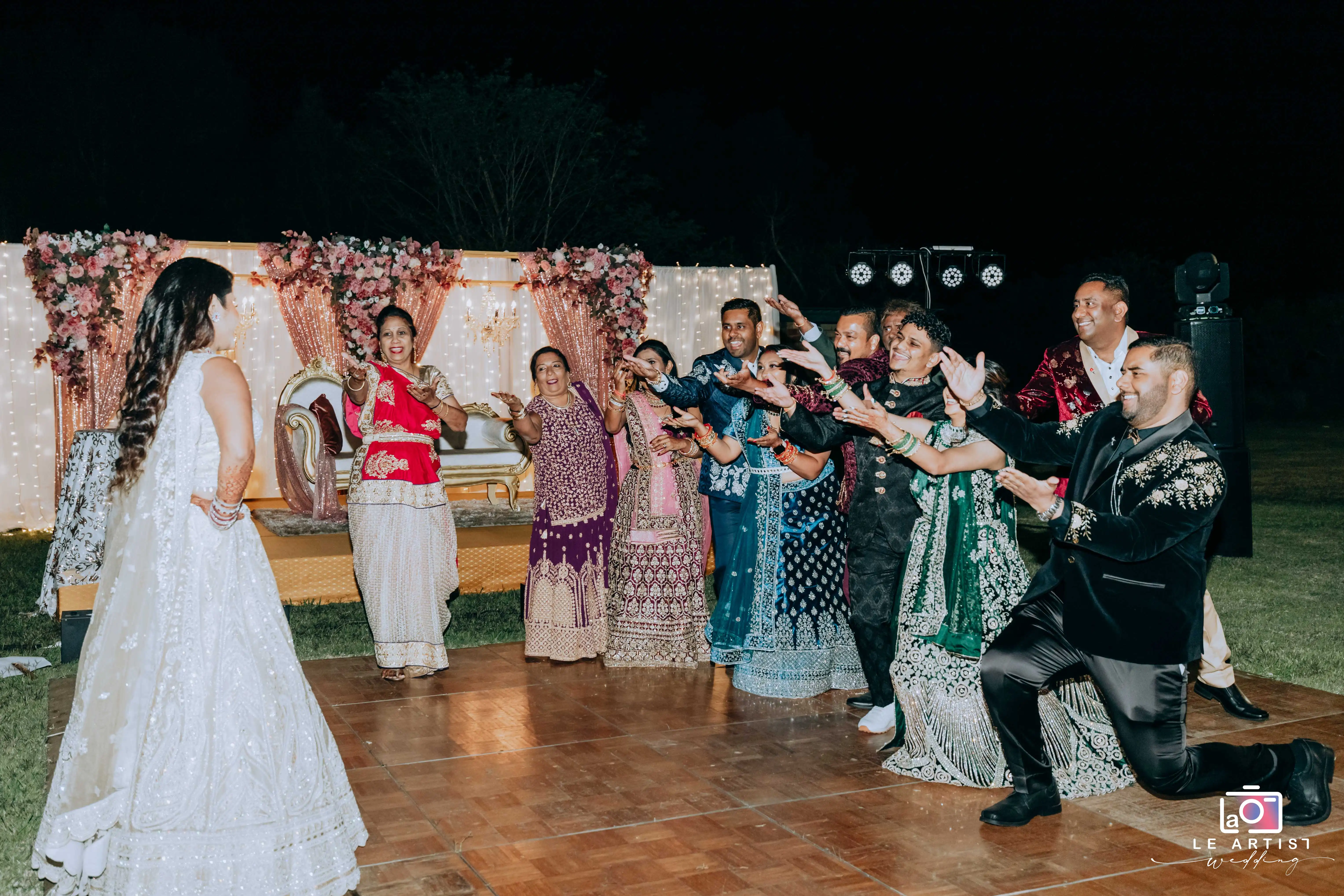 Guests enthusiastically welcome the bride to the dance floor during the reception, surrounded by elegant decor and bright lights. Le Artist Wedding