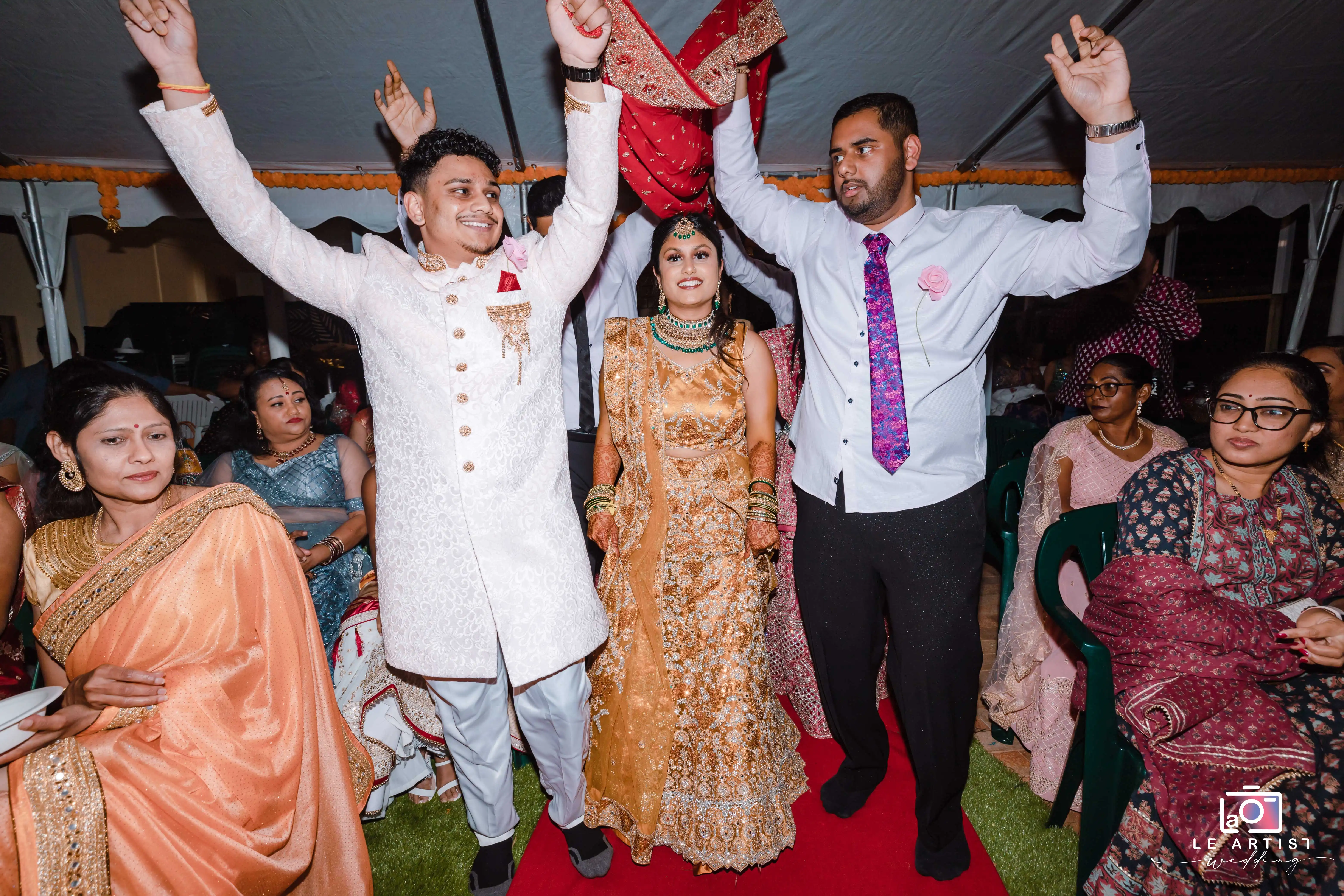 The bride and groom celebrating joyously with guests during the wedding reception. Le Artist Wedding