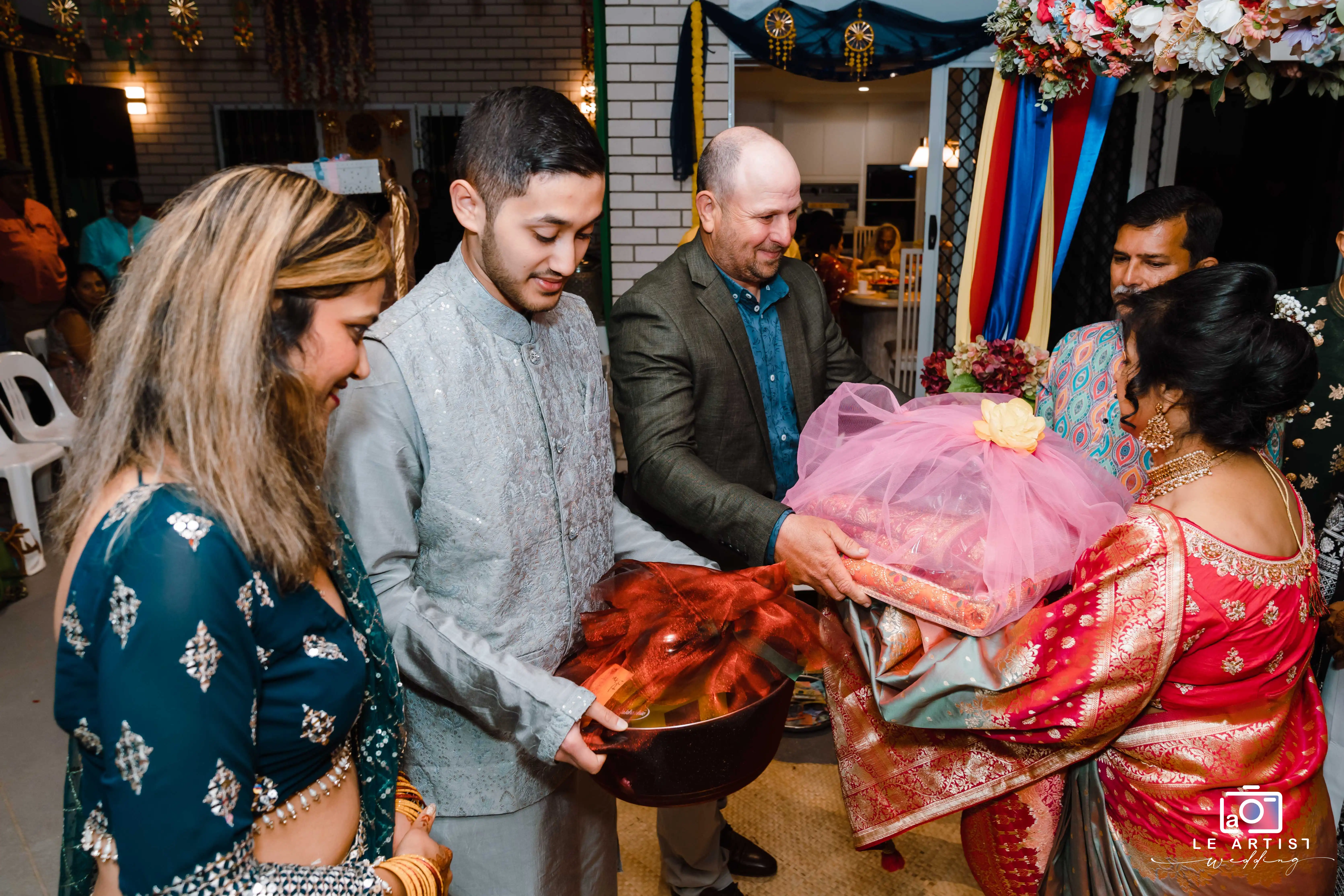 A vibrant moment from the wedding ceremony where guests exchange traditional gifts, symbolizing blessings and goodwill. Le Artist Wedding