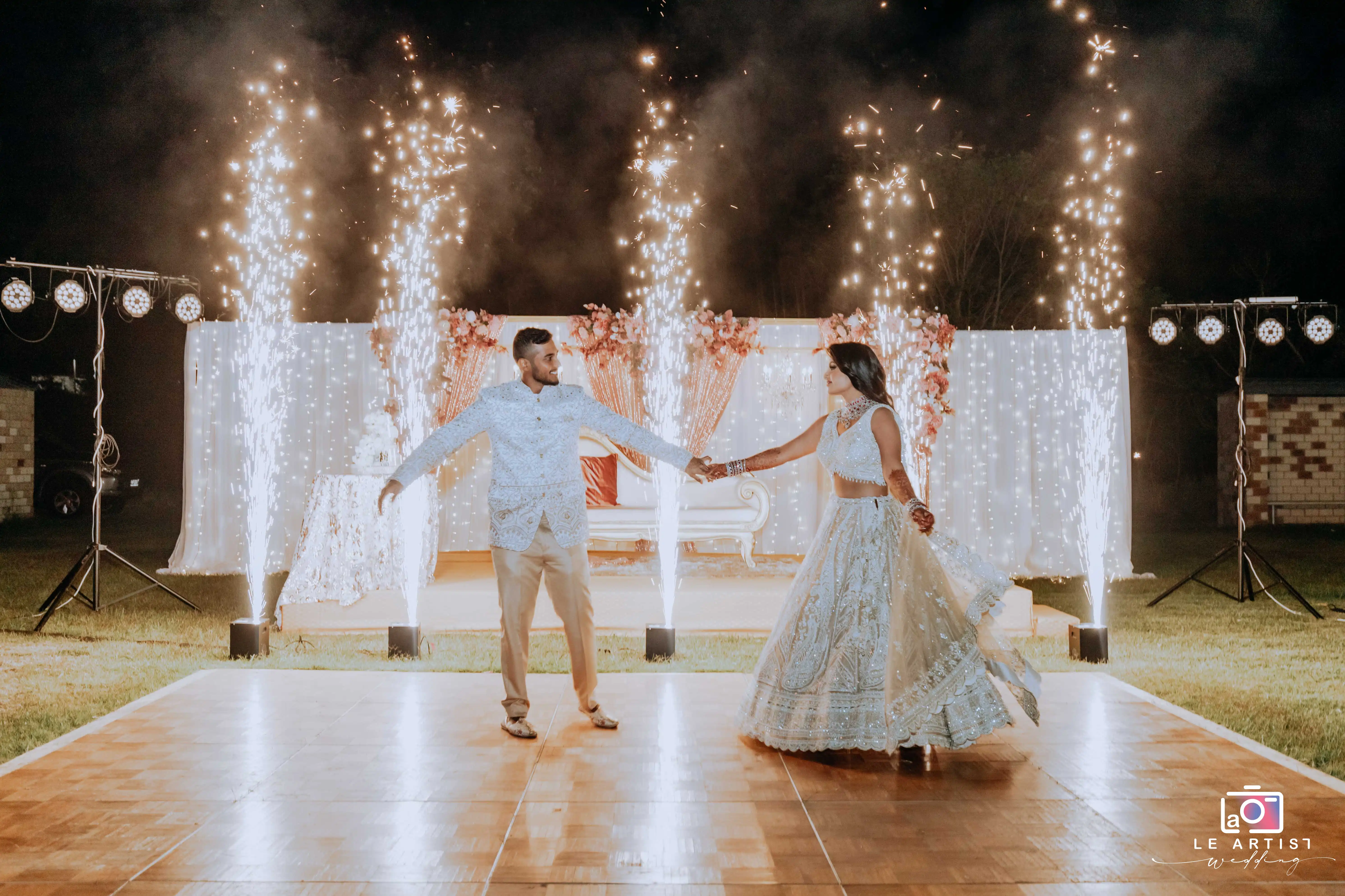 The couple shares a magical dance amidst sparkling fireworks during the reception. Le Artist Wedding