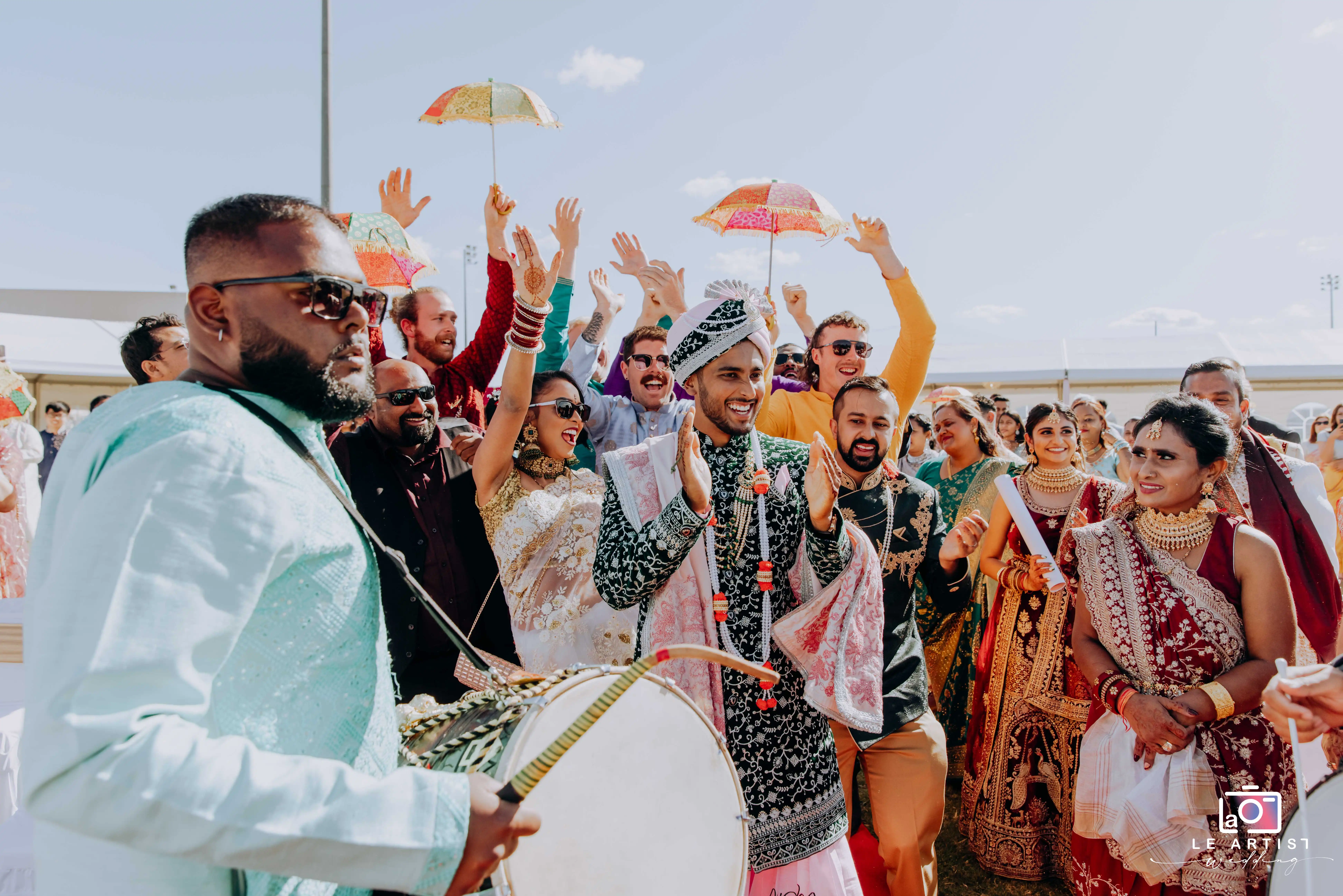 The groom is joyfully welcomed with music and dancing as friends and family celebrate during the vibrant baraat procession. Le Artist Wedding