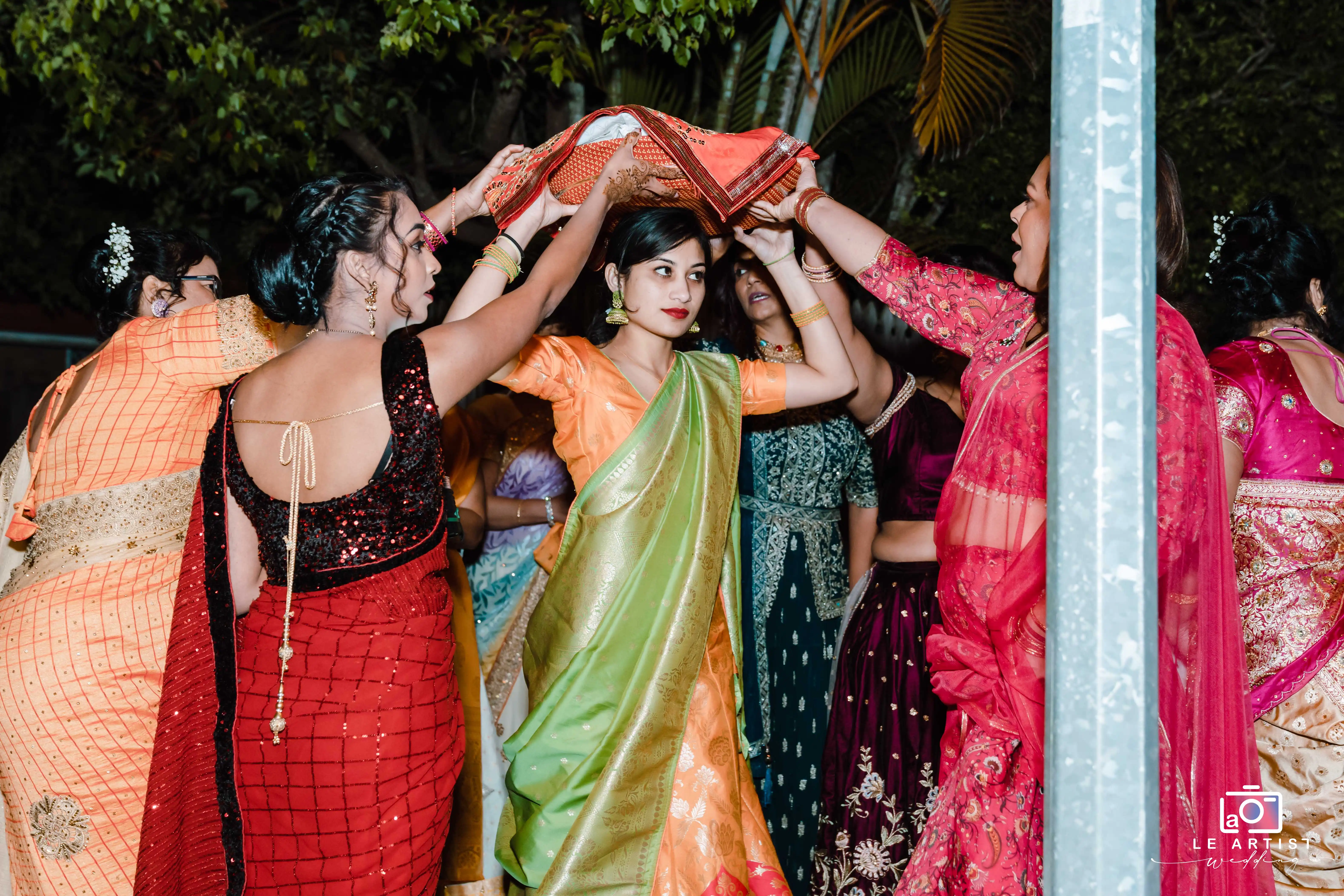 Guests engaged in a joyful dance, showcasing vibrant traditional attire at the wedding reception. Le Artist Wedding