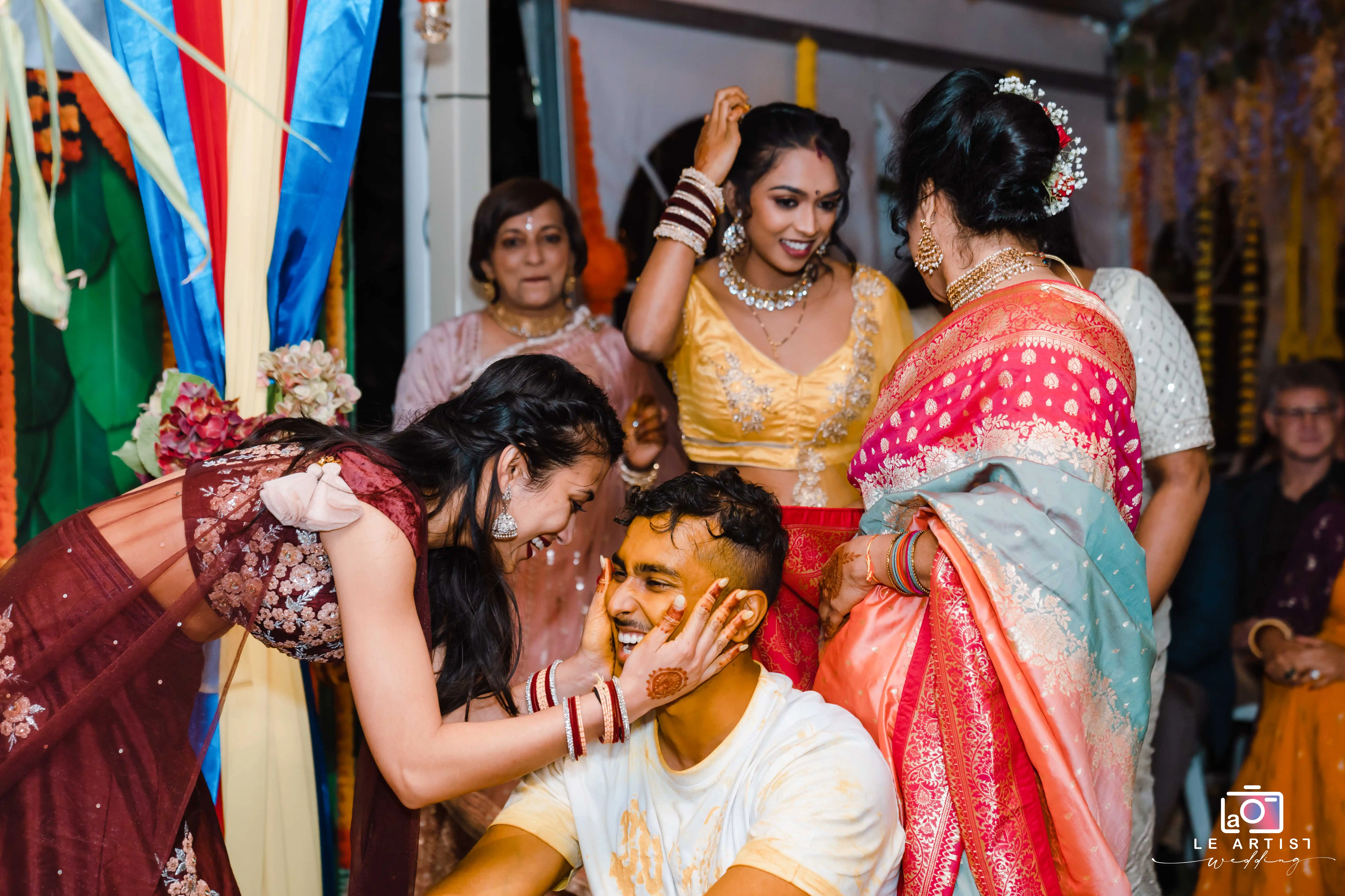 Friends and family sharing a joyful moment during the wedding festivities, surrounded by colorful decorations and traditional attire. Le Artist Wedding