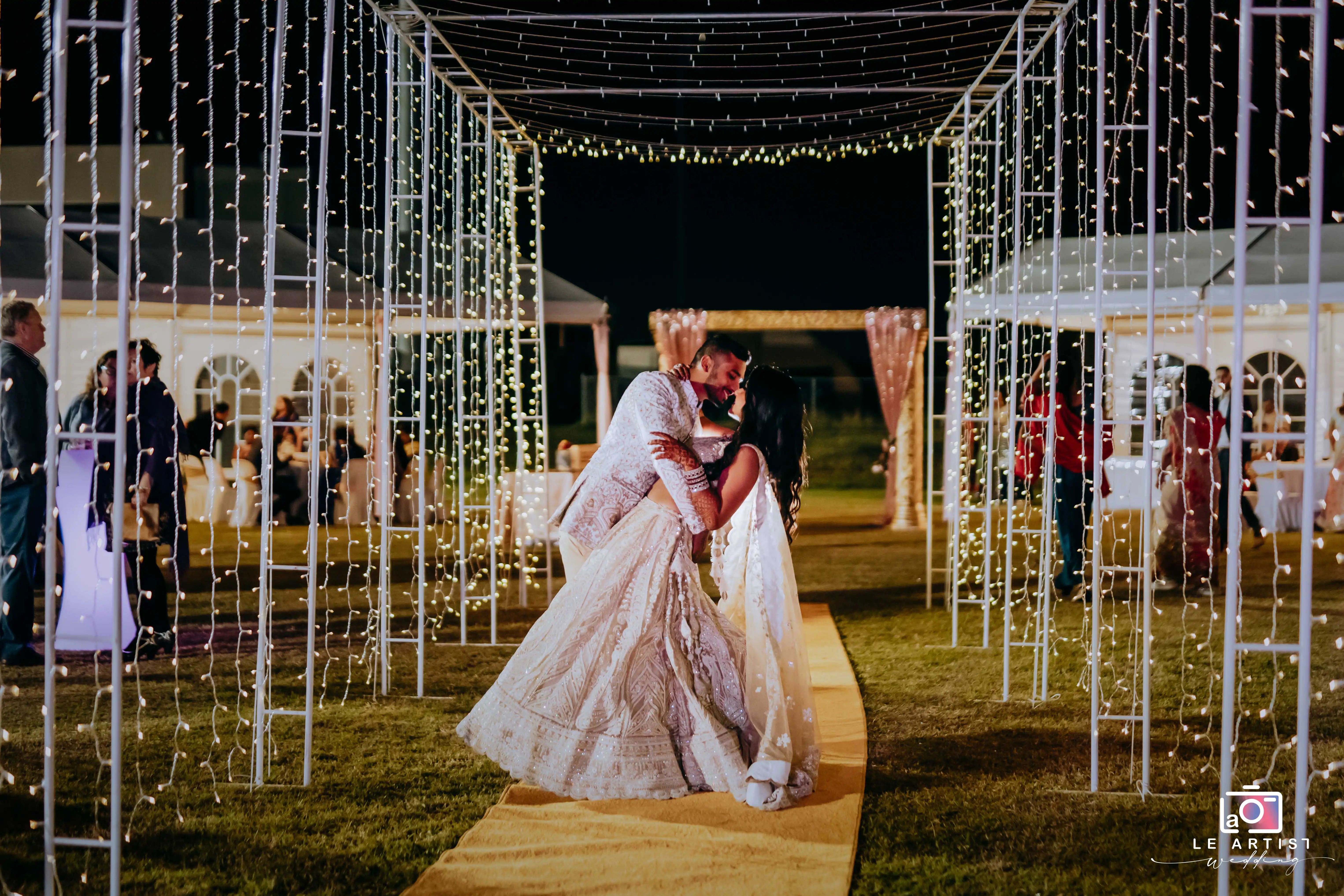 The couple shares a romantic dance under a canopy of twinkling lights during the wedding reception. Le Artist Wedding
