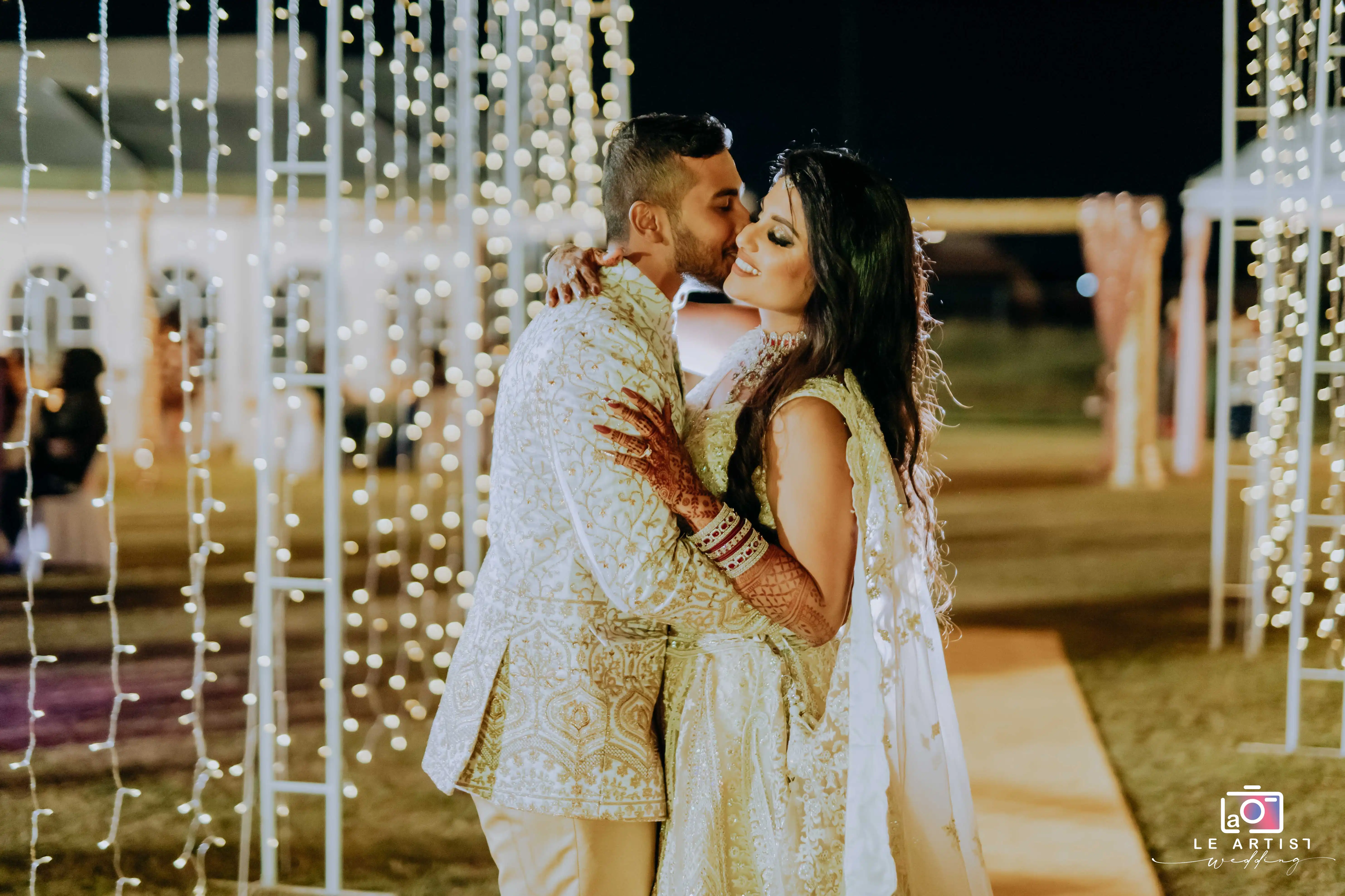 The couple shares a romantic moment underneath twinkling lights during the wedding reception. Le Artist Wedding