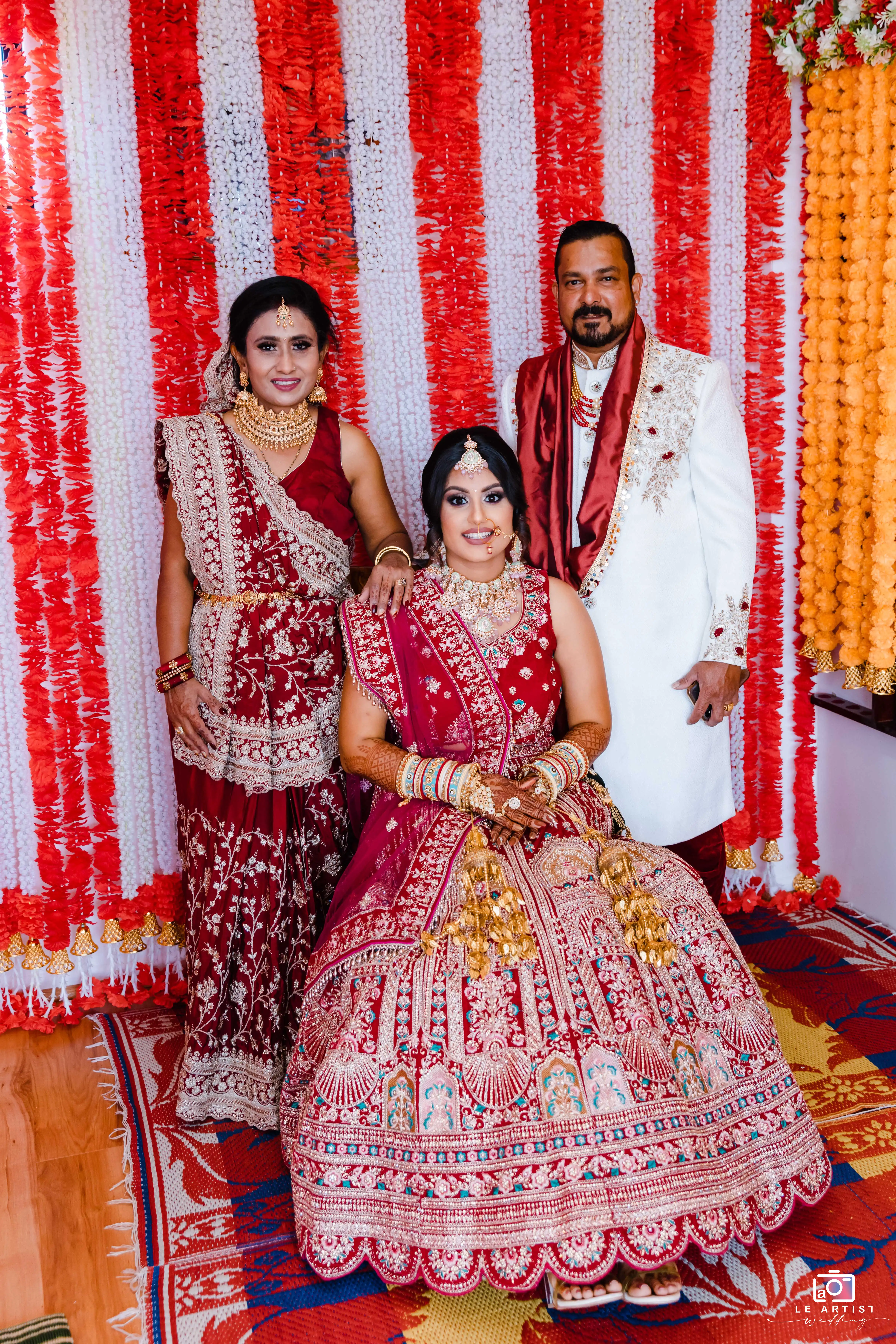 The bridal party poses elegantly in traditional attire against a vibrant backdrop, showcasing intricate designs and rich colors. Le Artist Wedding