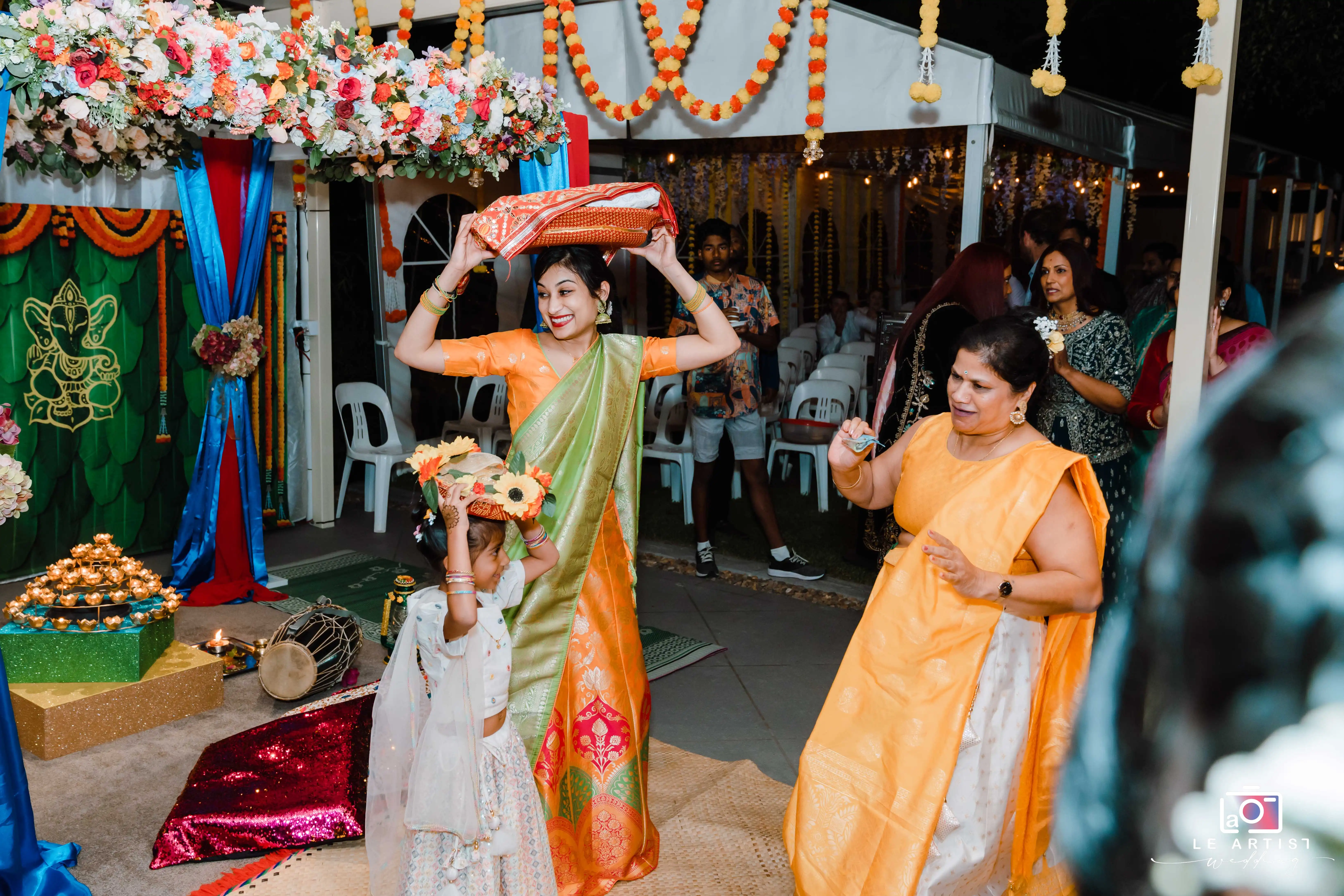 A joyous moment during a traditional wedding ceremony featuring vibrant attire and festive decorations. Le Artist Wedding
