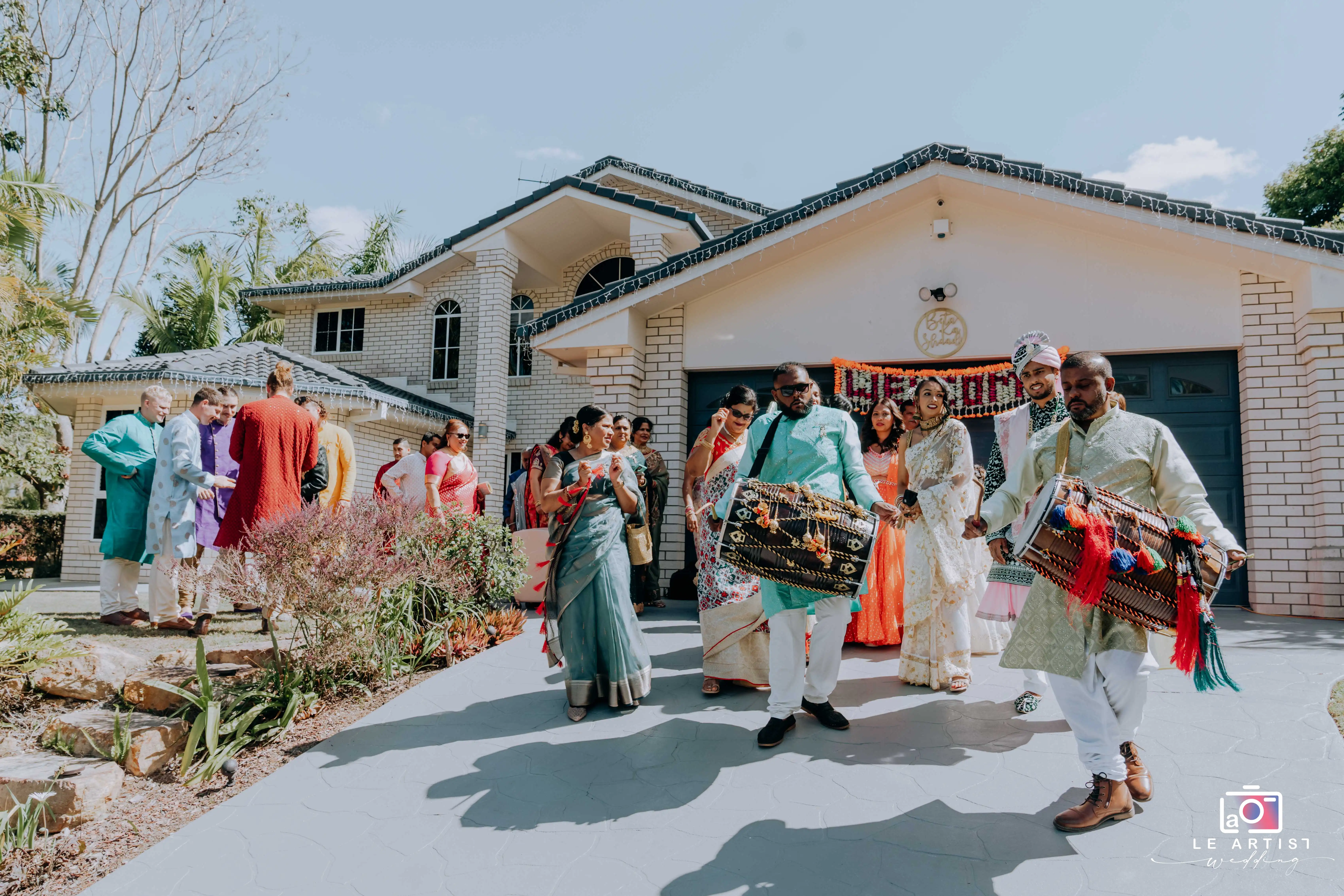 The vibrant wedding procession arrives with traditional music and colorful attire, setting the celebratory tone before the ceremony. Le Artist Wedding