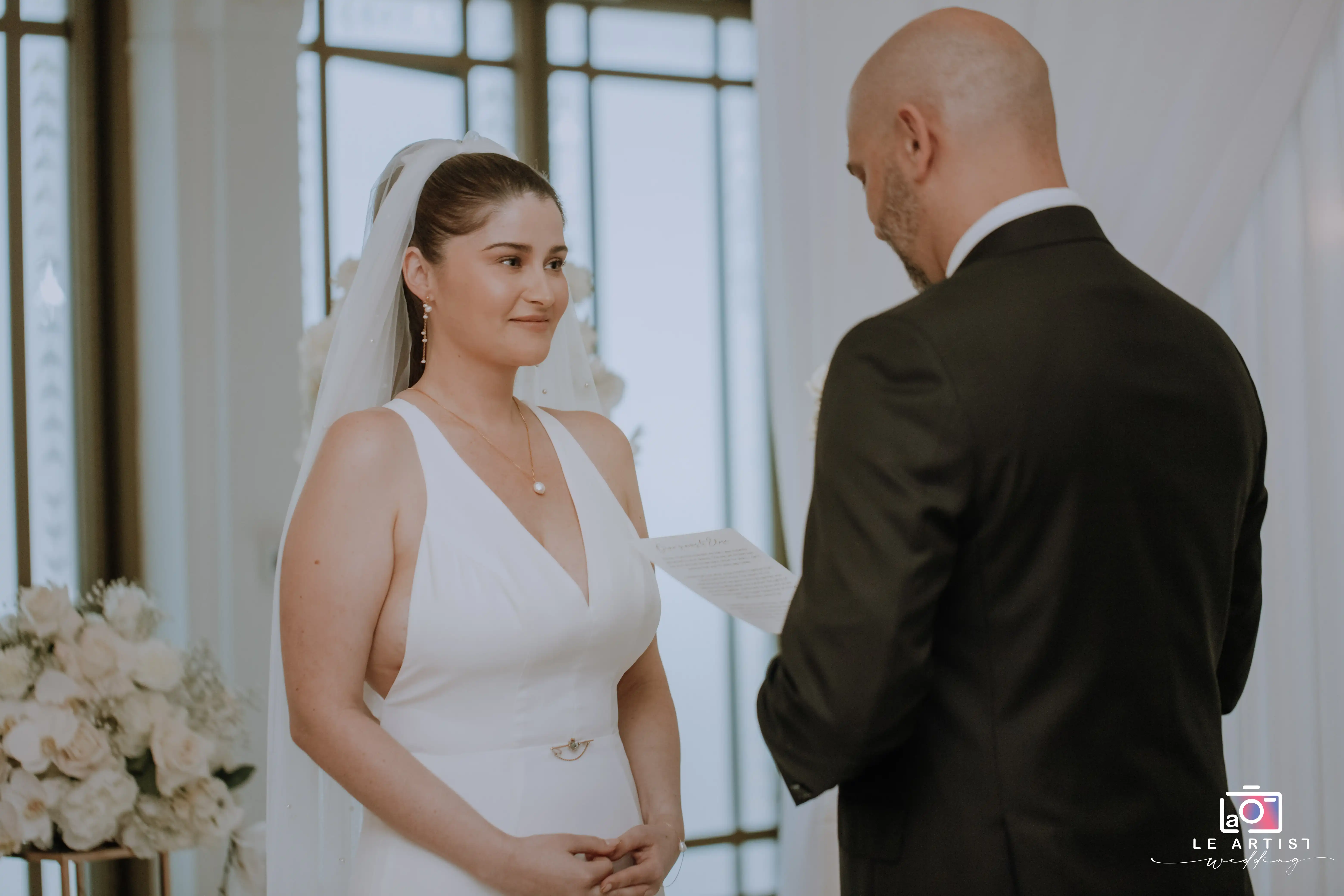 The bride and groom exchange heartfelt vows during their wedding ceremony, capturing a moment of love and commitment. Le Artist Wedding
