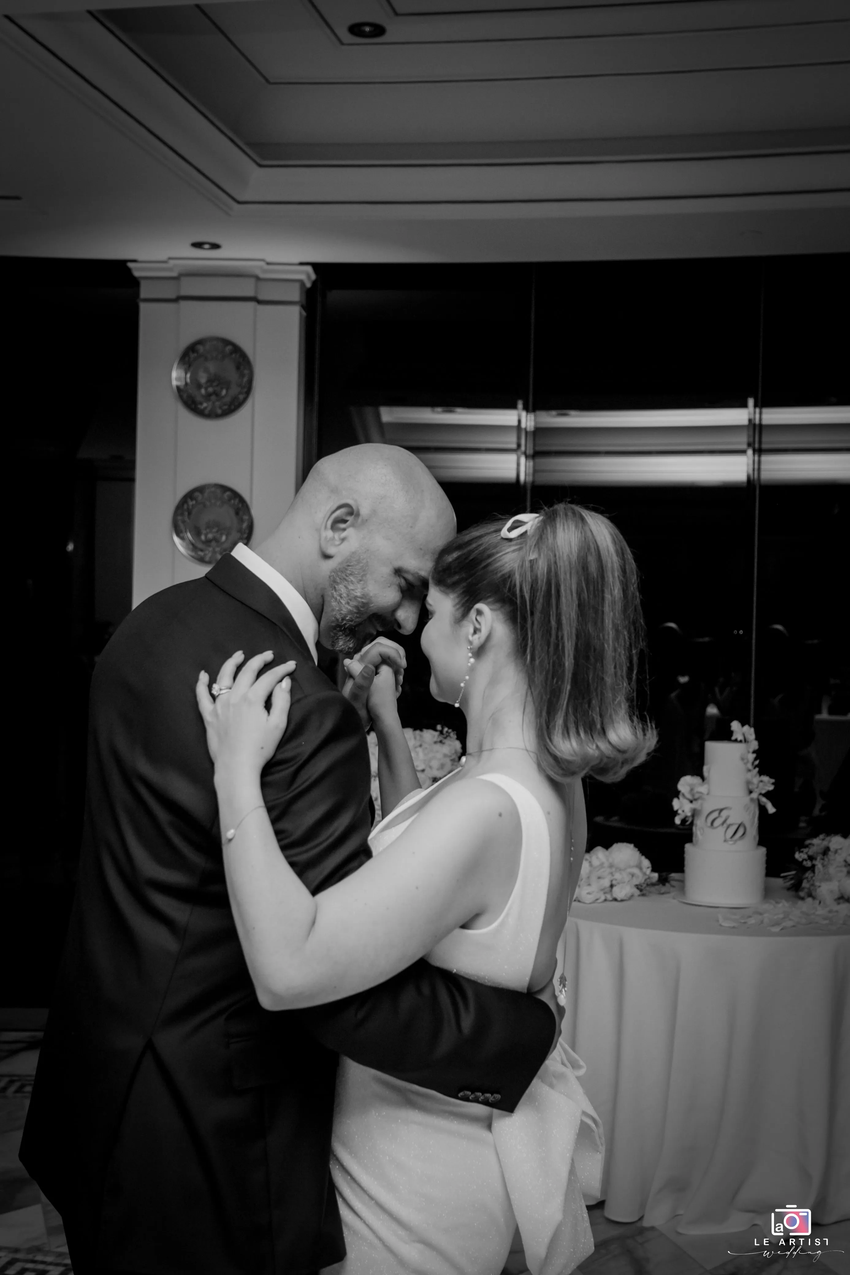 The bride and groom share a quiet, intimate moment on the dance floor during their wedding reception. Le Artist Wedding