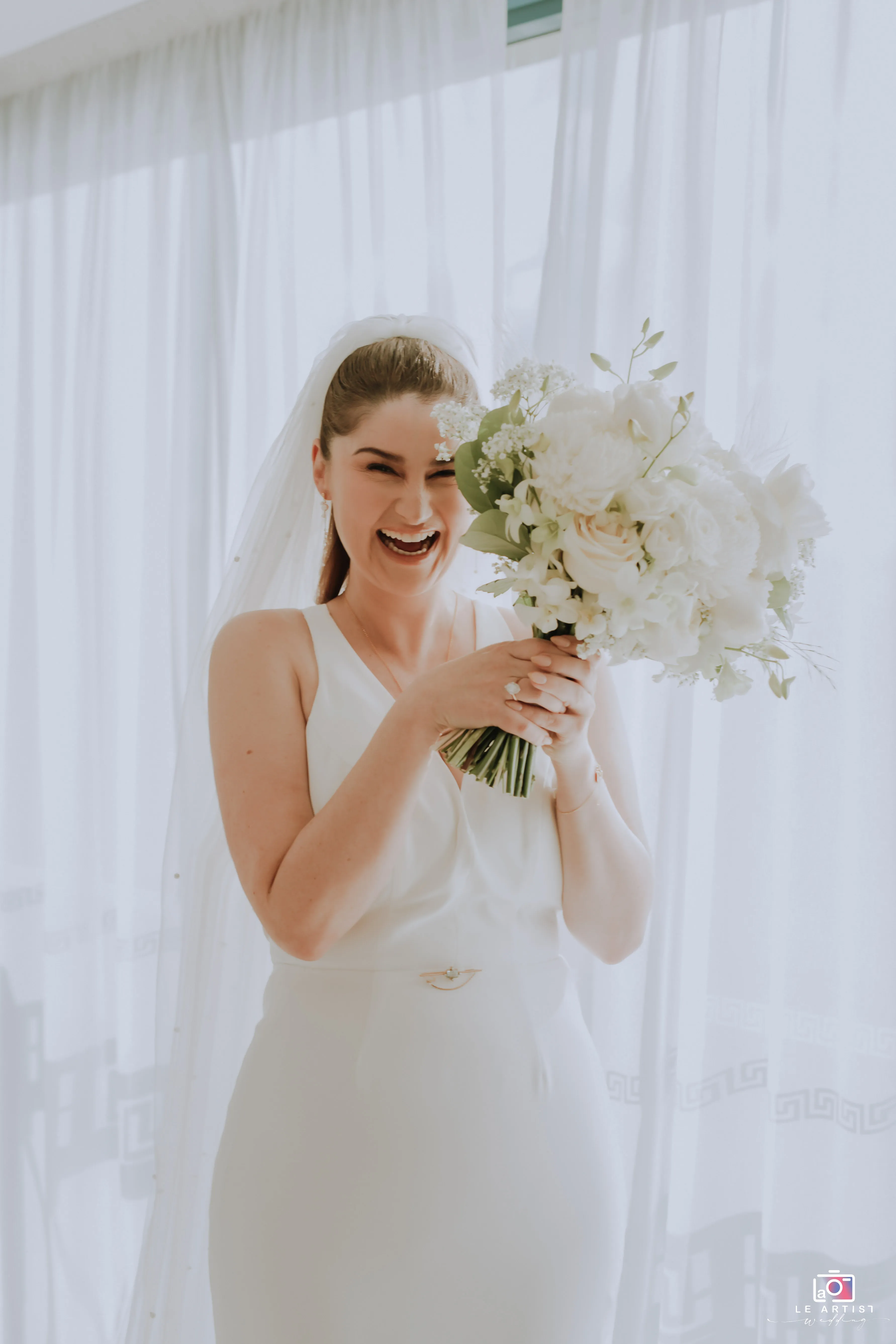 The bride joyfully holds her bouquet during a bright bridal photoshoot. Le Artist Wedding