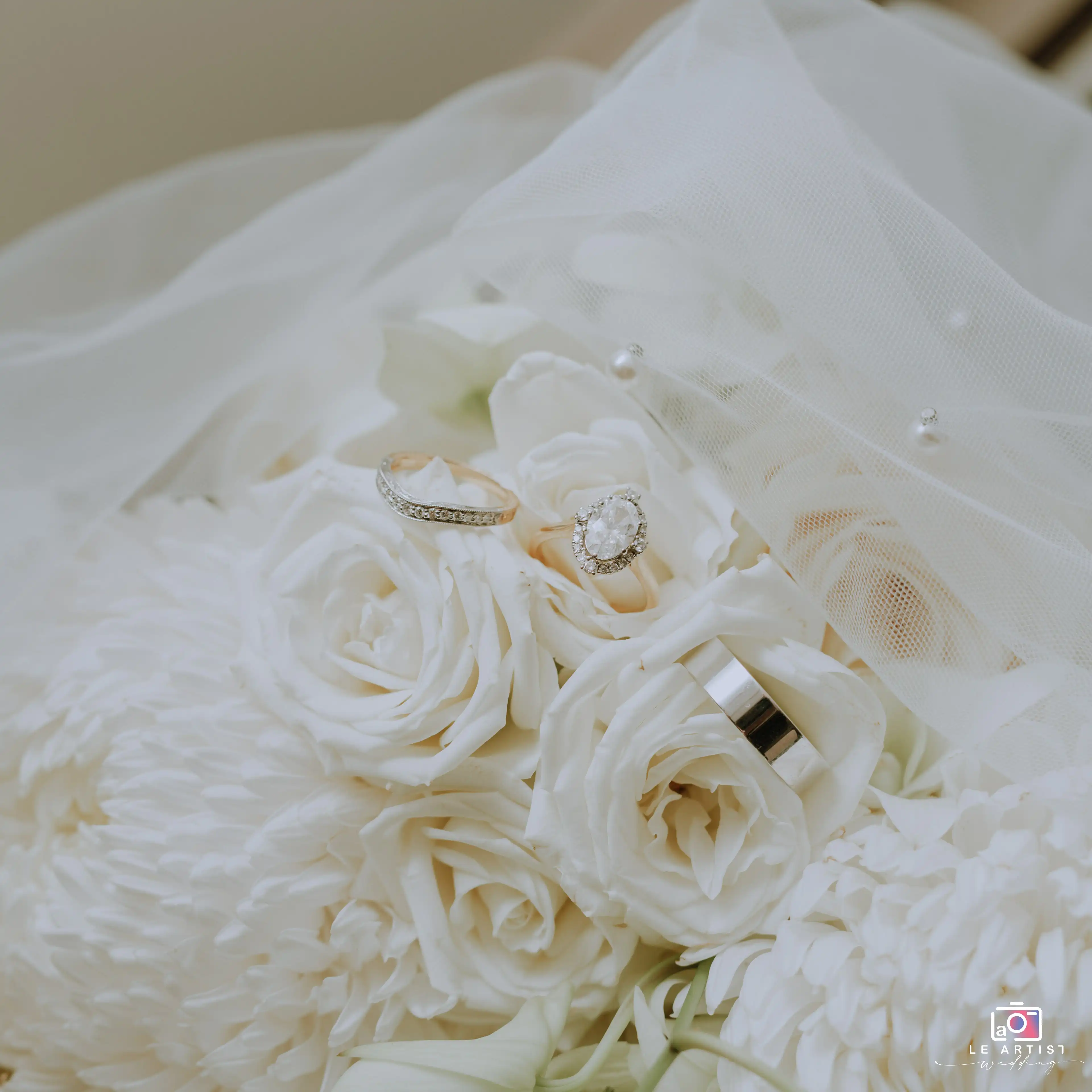 A beautifully arranged bridal bouquet with the wedding rings elegantly placed atop, capturing the essence of the 'getting ready' moment. Le Artist Wedding