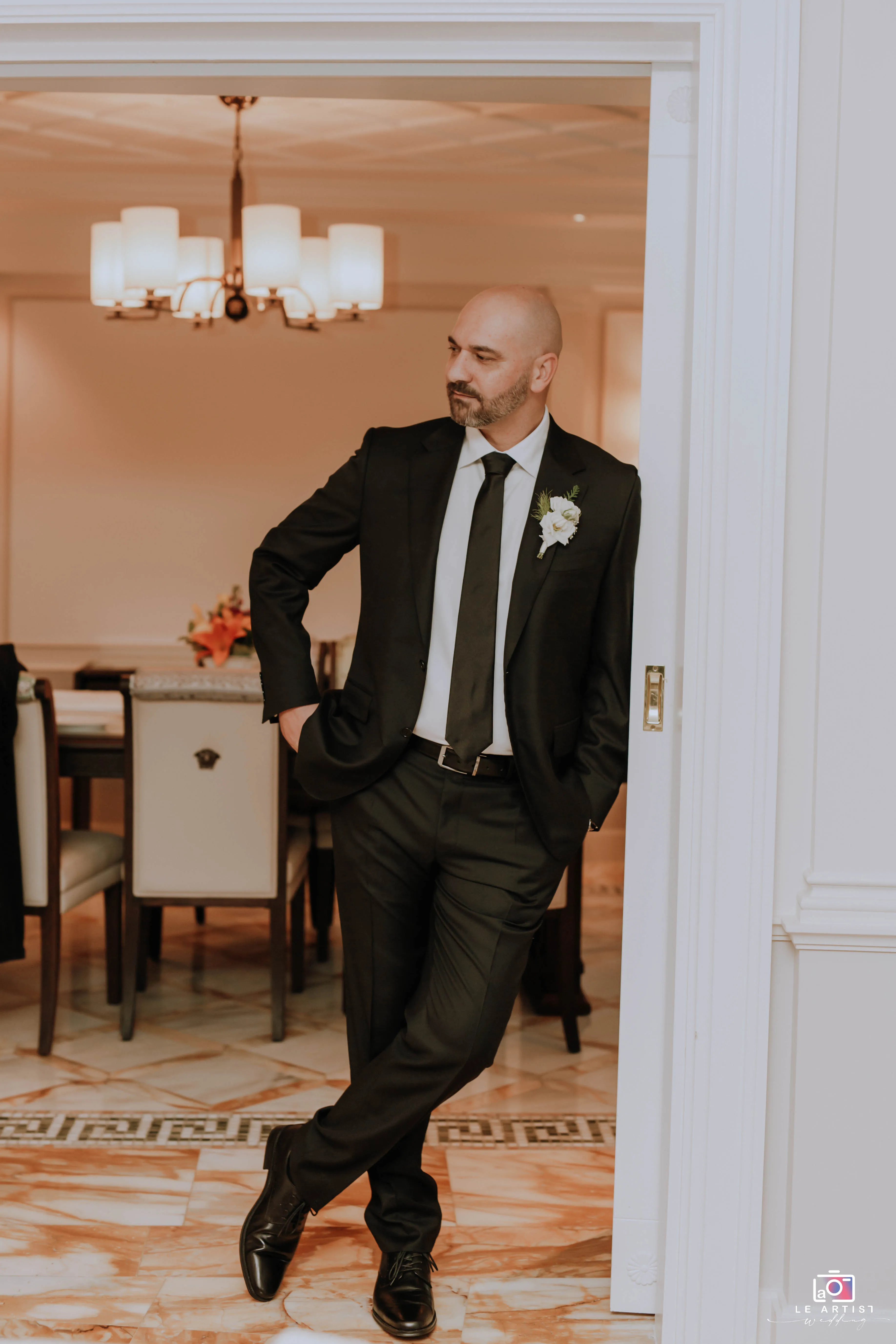 The groom poses confidently as he gets ready for the big day, showcasing a moment of calm anticipation. Le Artist Wedding