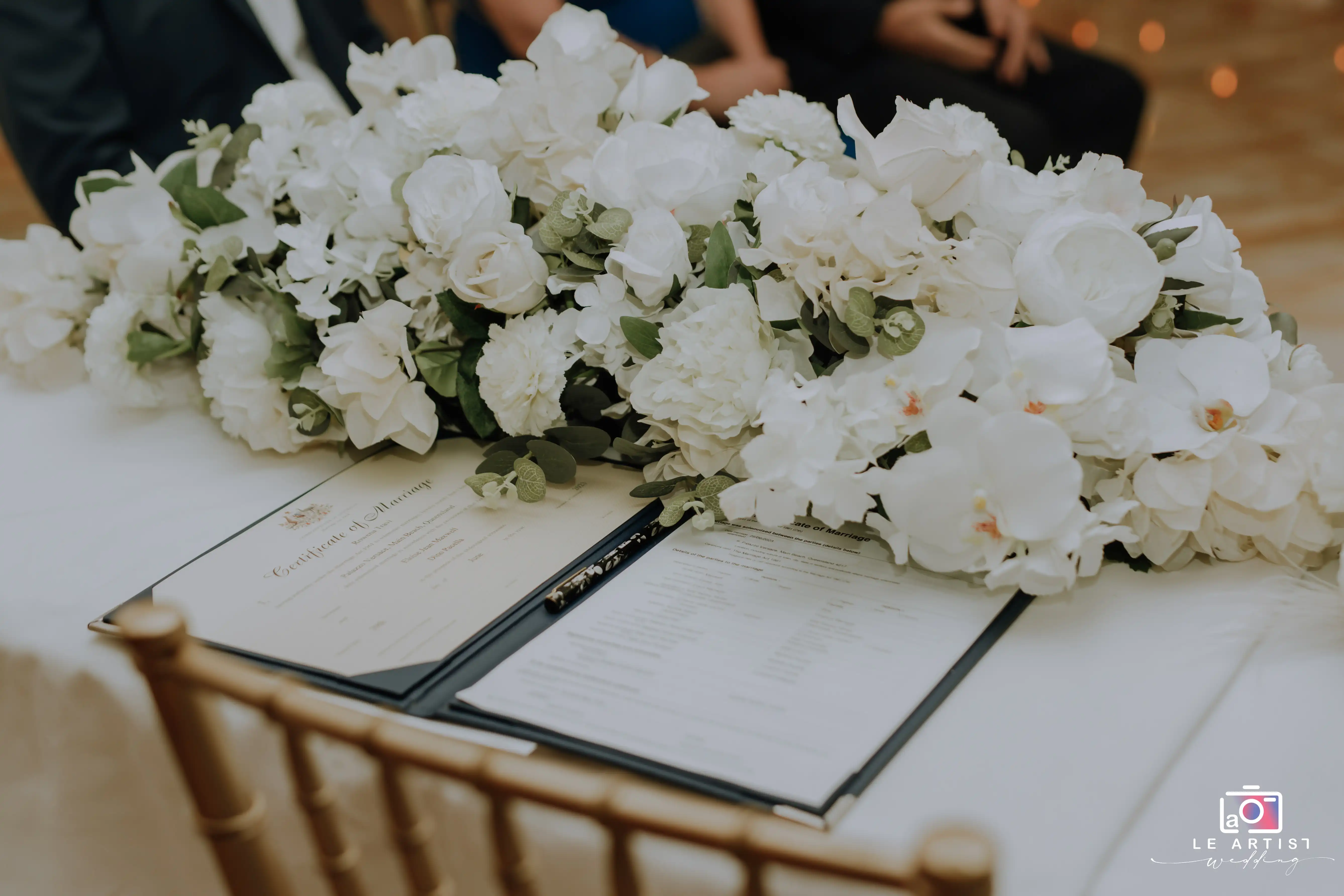 A beautifully decorated table with a marriage certificate ready for signing, marking a significant moment in the wedding ceremony. Le Artist Wedding