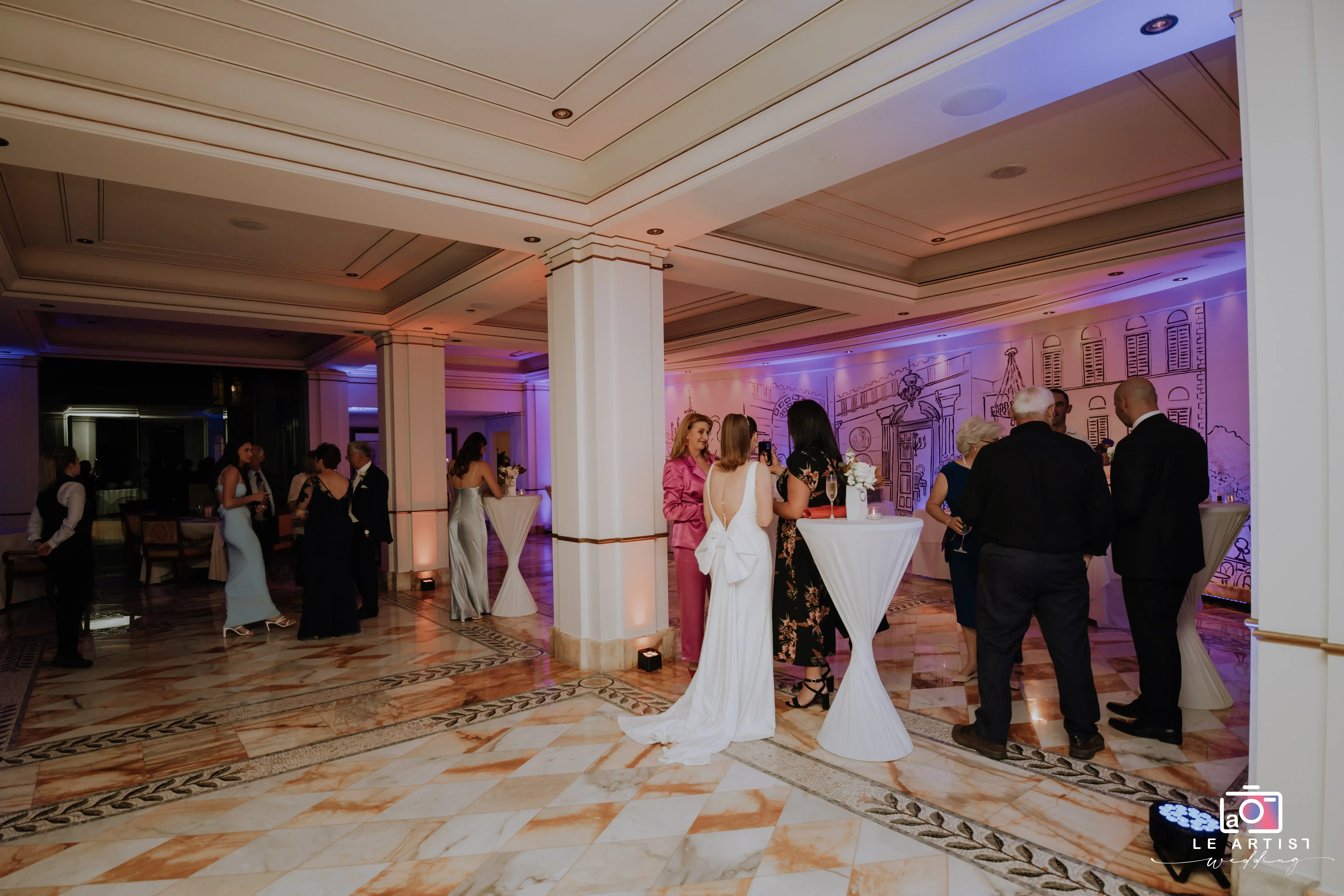 Guests mingle during the wedding reception, enjoying drinks and conversation in a beautifully decorated venue. Le Artist Wedding