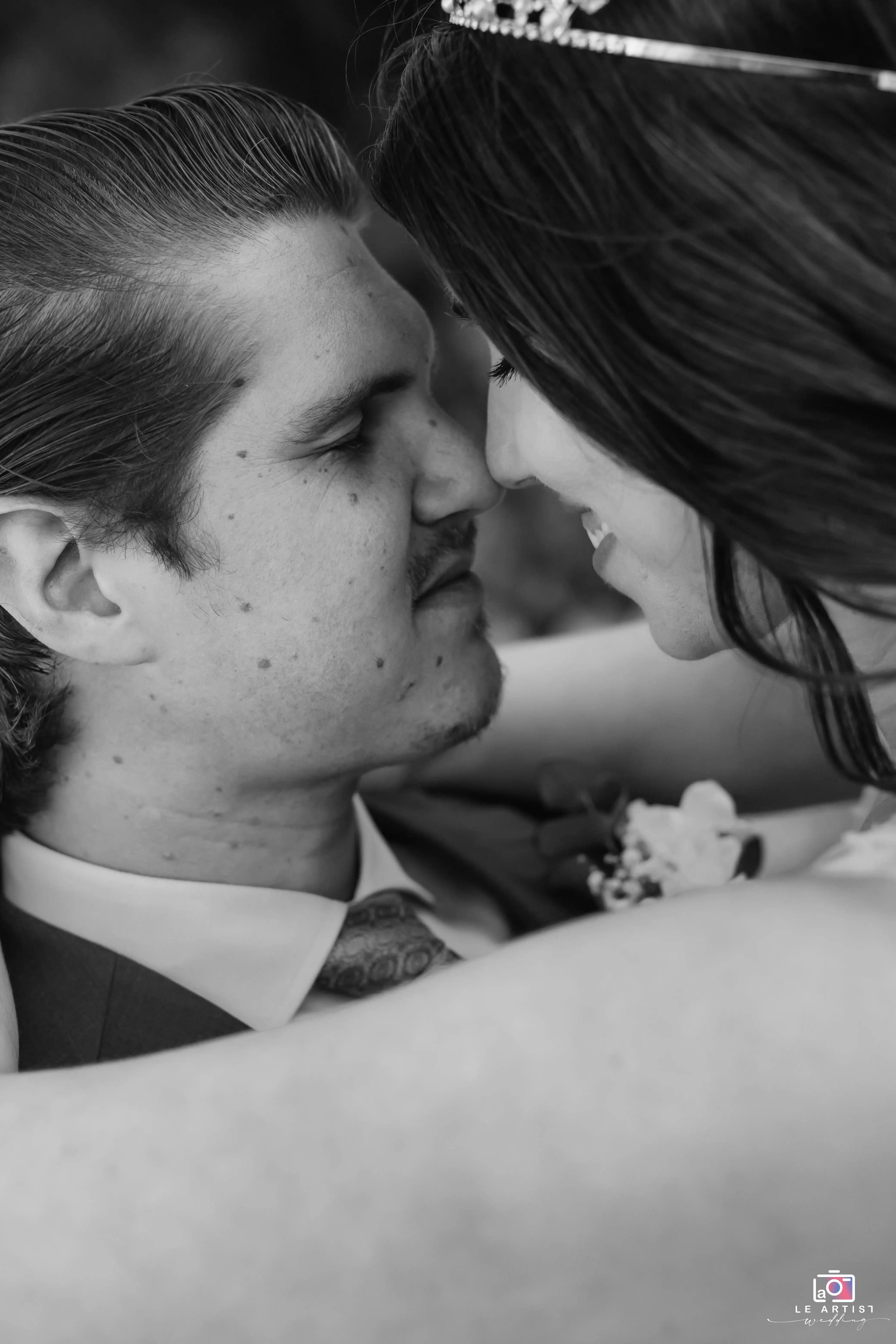 A tender black-and-white close-up captures the bride and groom sharing an intimate embrace, highlighting their joy and connection. Le Artist Wedding