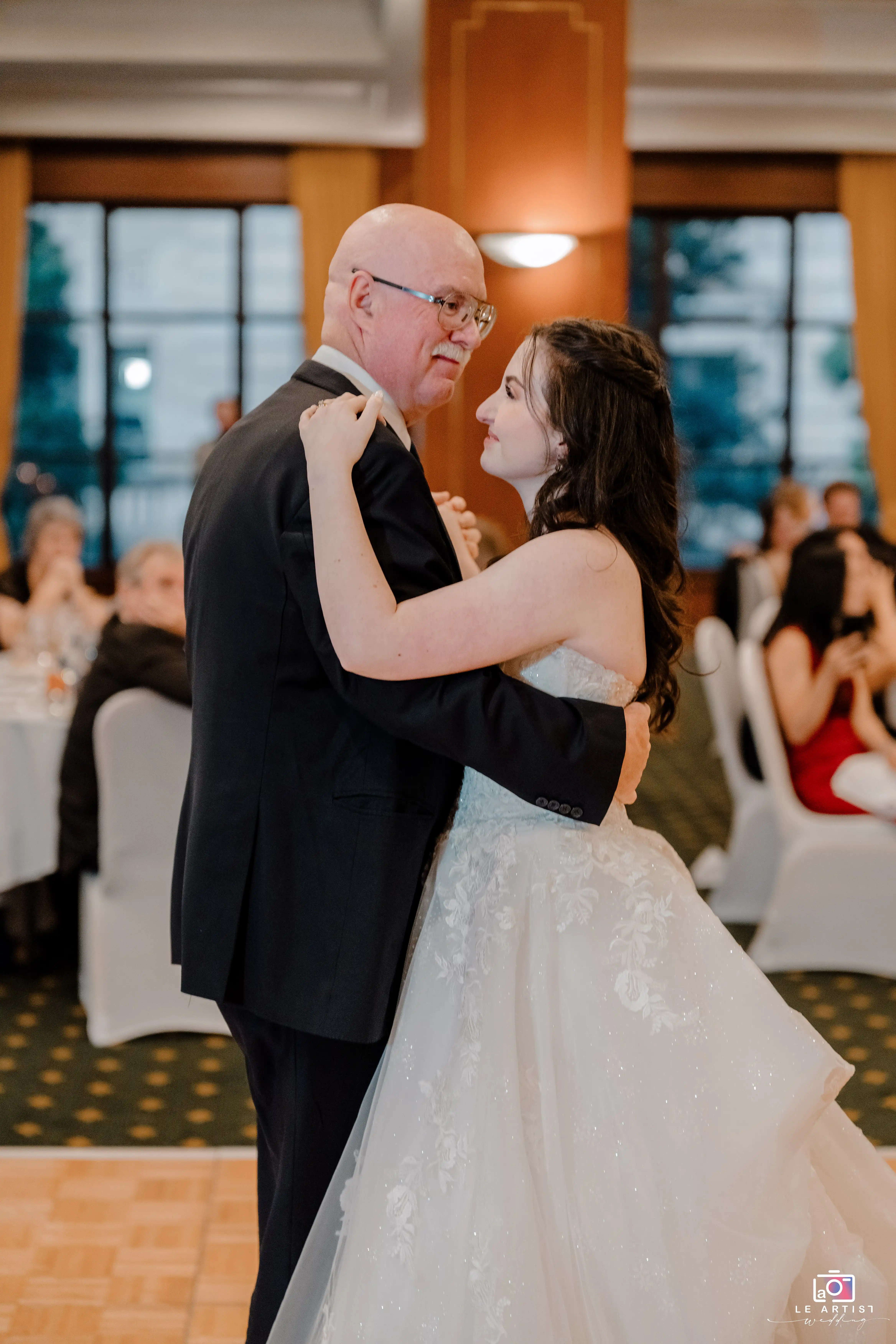 A touching moment as the bride shares a dance with her father, surrounded by the warm ambiance of the wedding reception. Le Artist Wedding