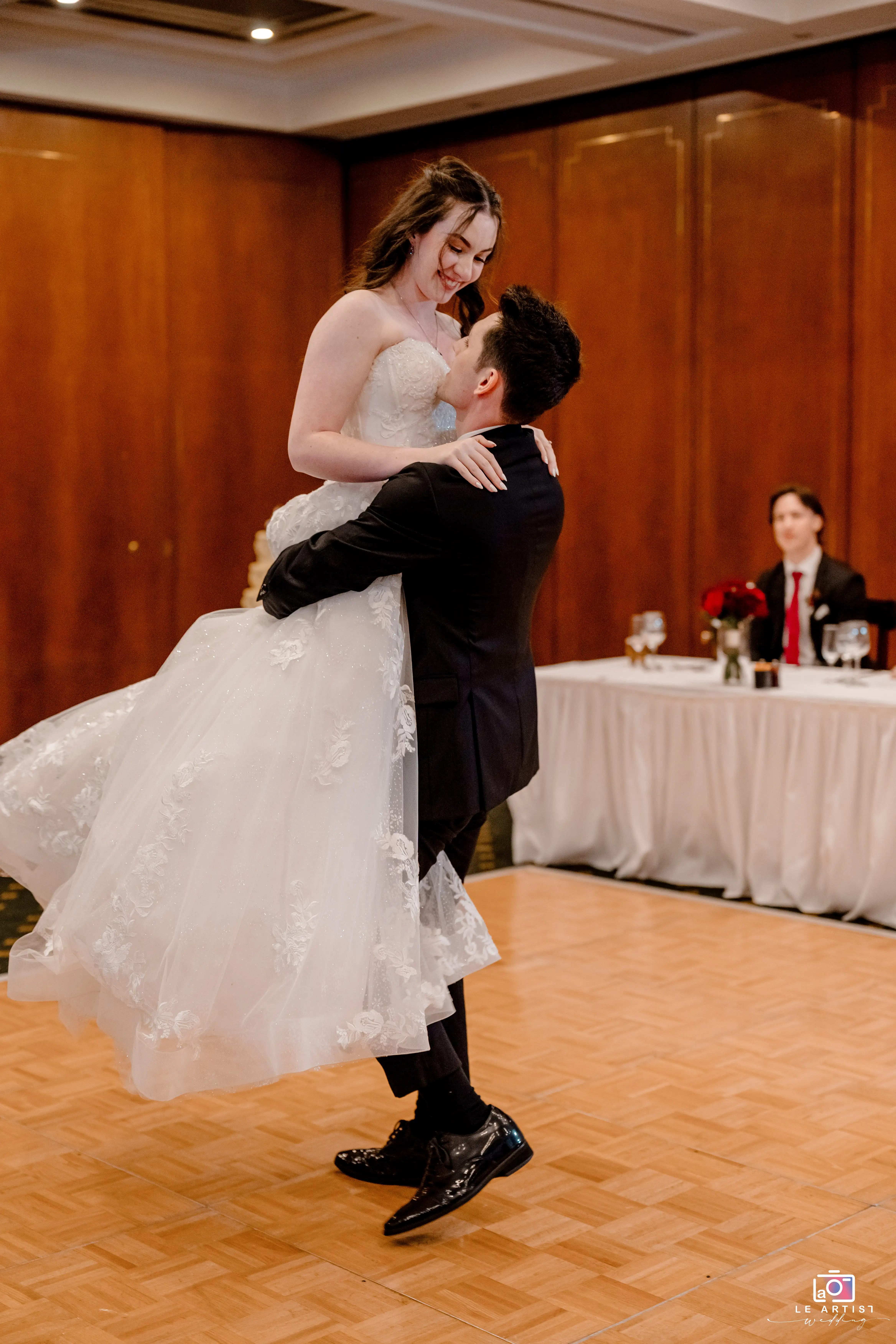 The groom lifts the bride joyfully during a delightful moment on the dance floor. Le Artist Wedding