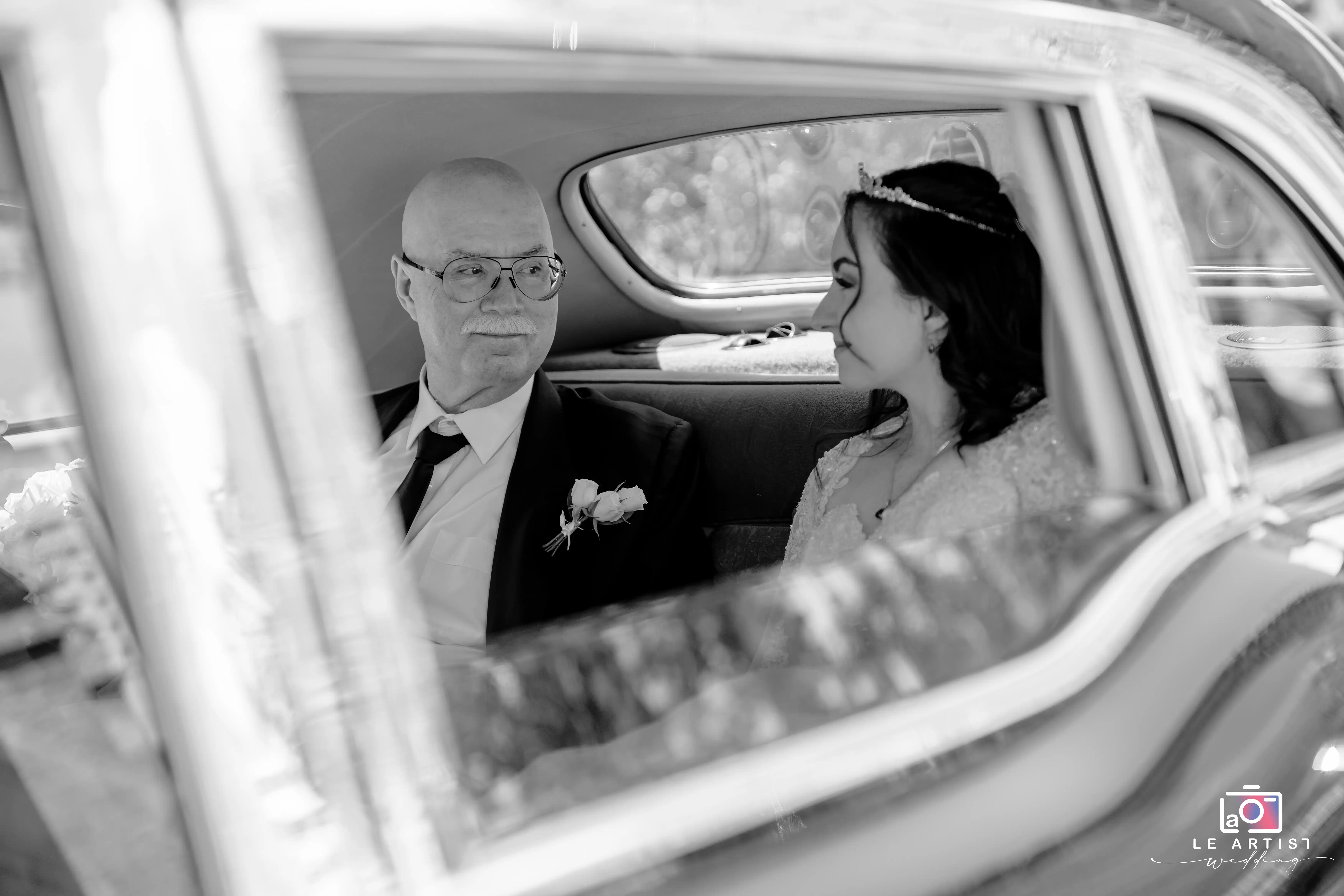 A serene moment captured between the bride and a family member as they sit together in a classic car, reflecting the anticipation and emotion of the day. Le Artist Wedding
