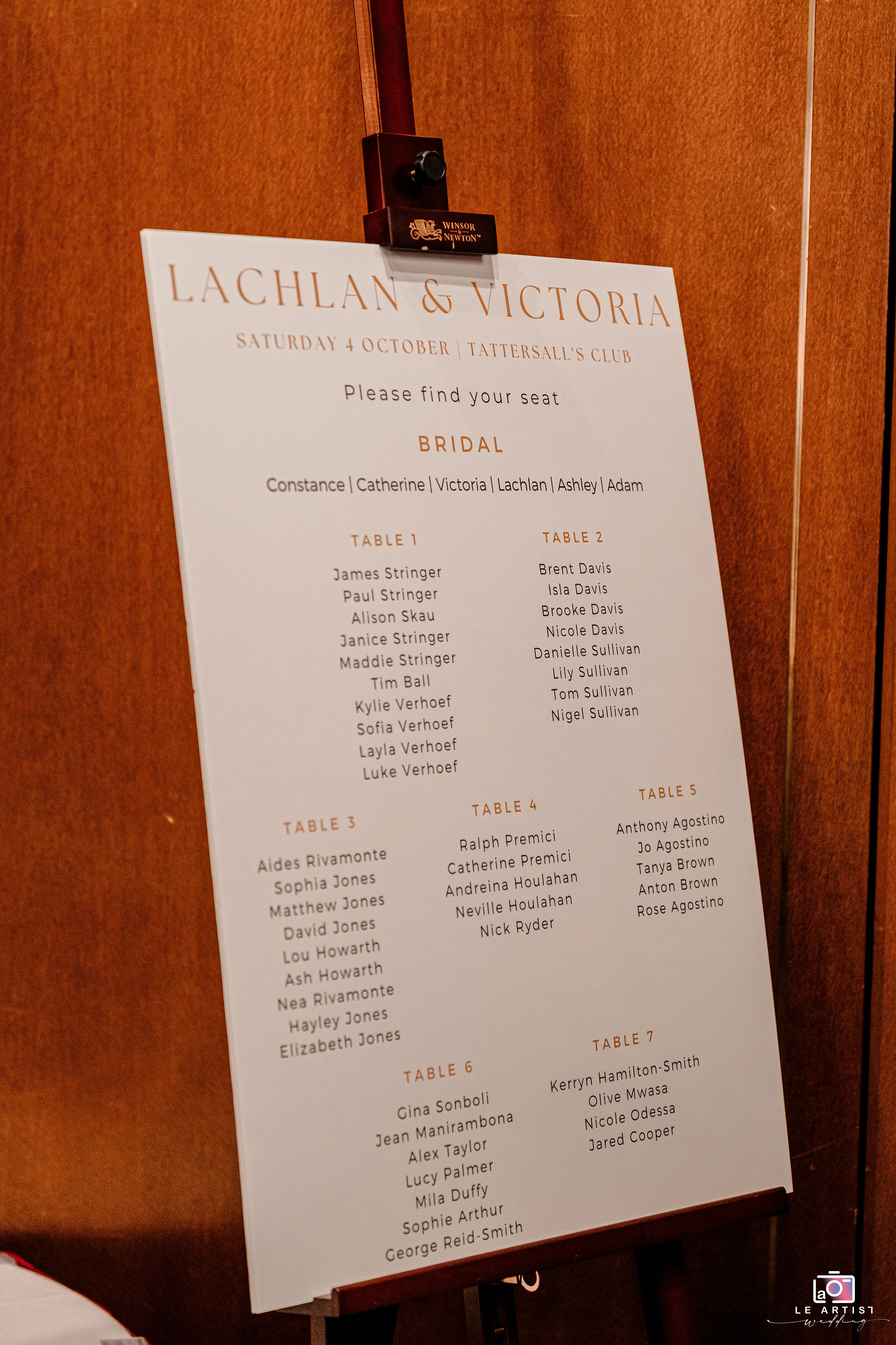 A wedding seating chart displayed elegantly on an easel, helping guests find their designated tables at the reception in Tattersall's Club. Le Artist Wedding