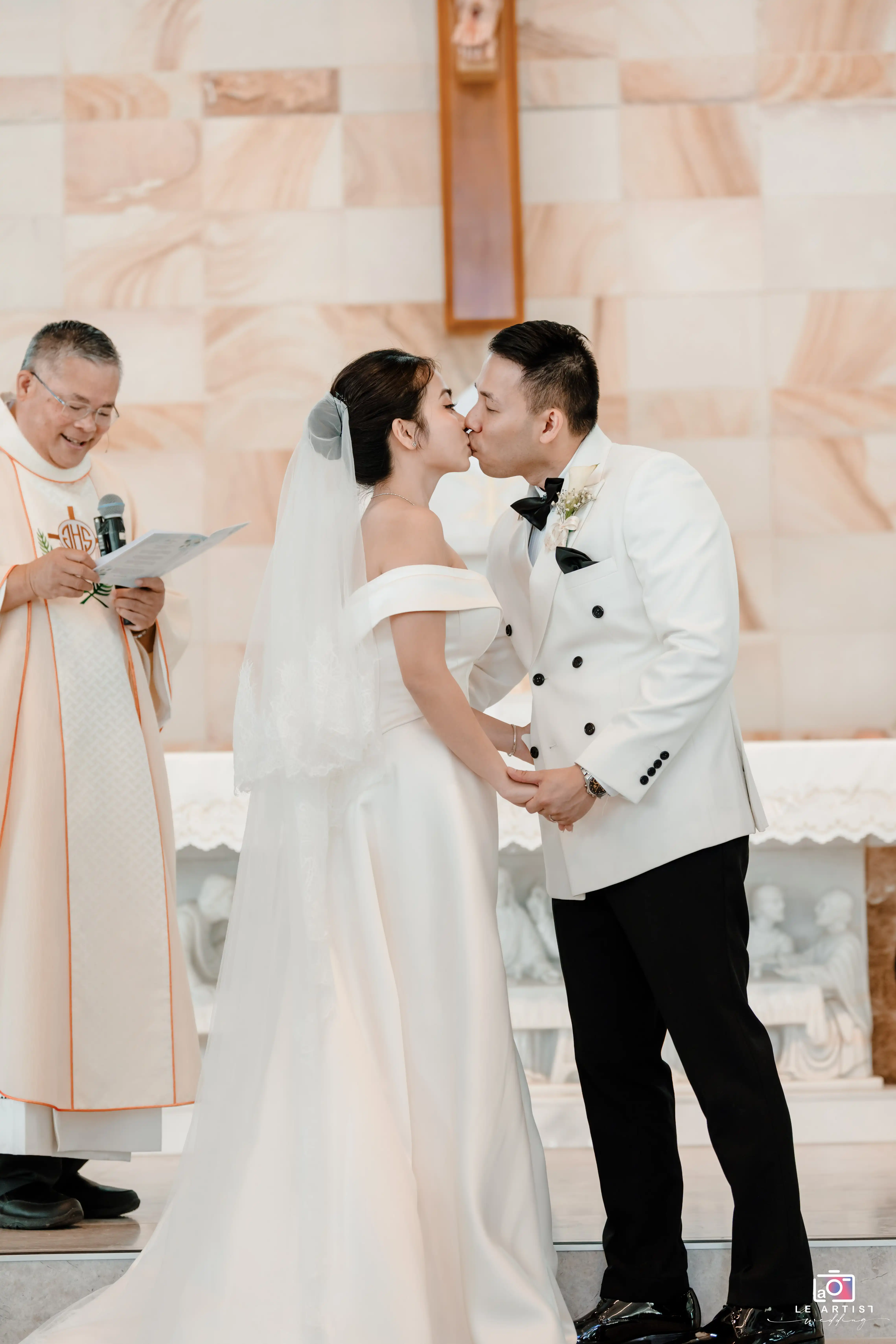 The couple shares their ceremonial kiss in front of the officiant, marking the beginning of their new life together. Le Artist Wedding