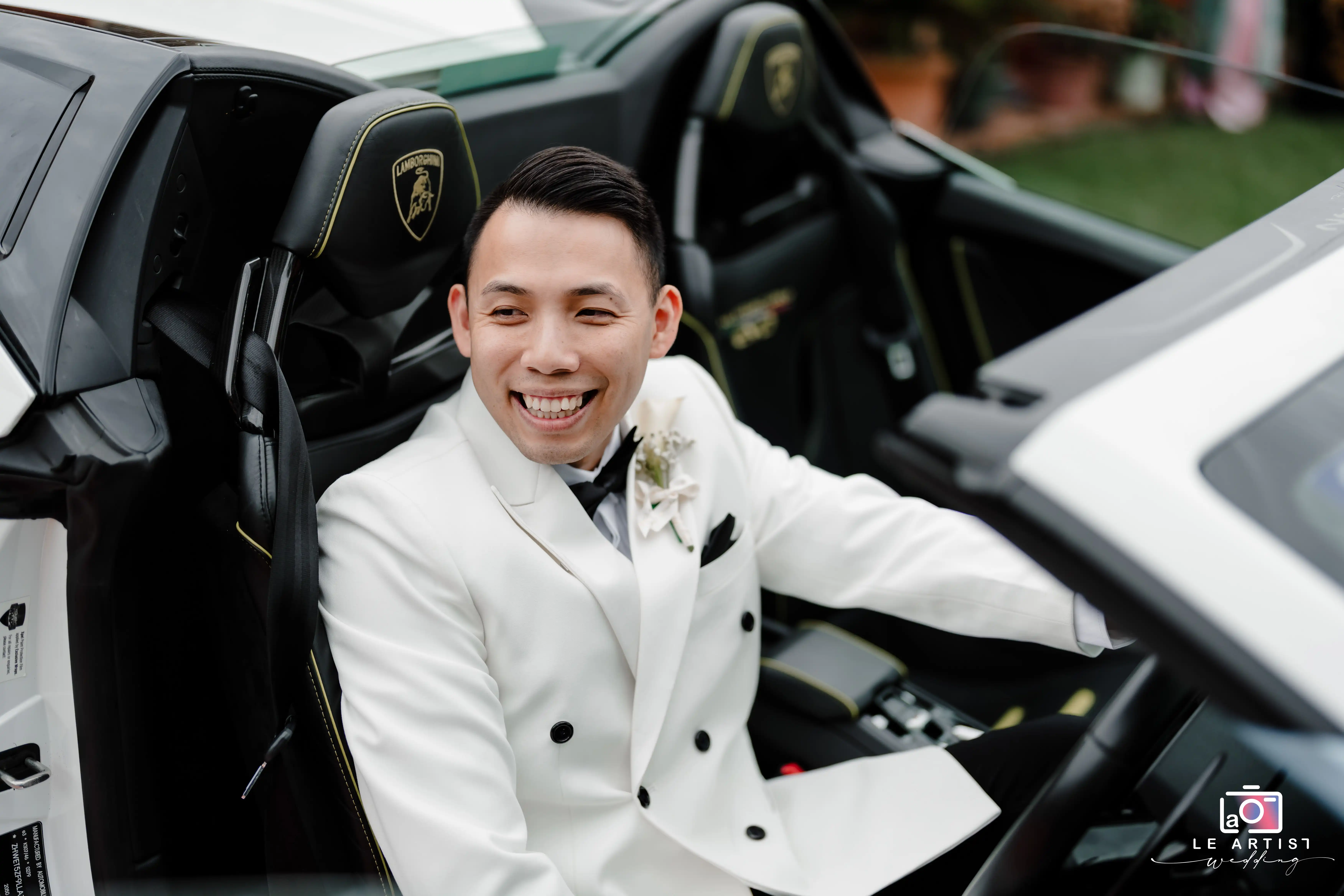 The groom smiles confidently while seated in a luxurious convertible, enhancing the elegance of the wedding day. Le Artist Wedding