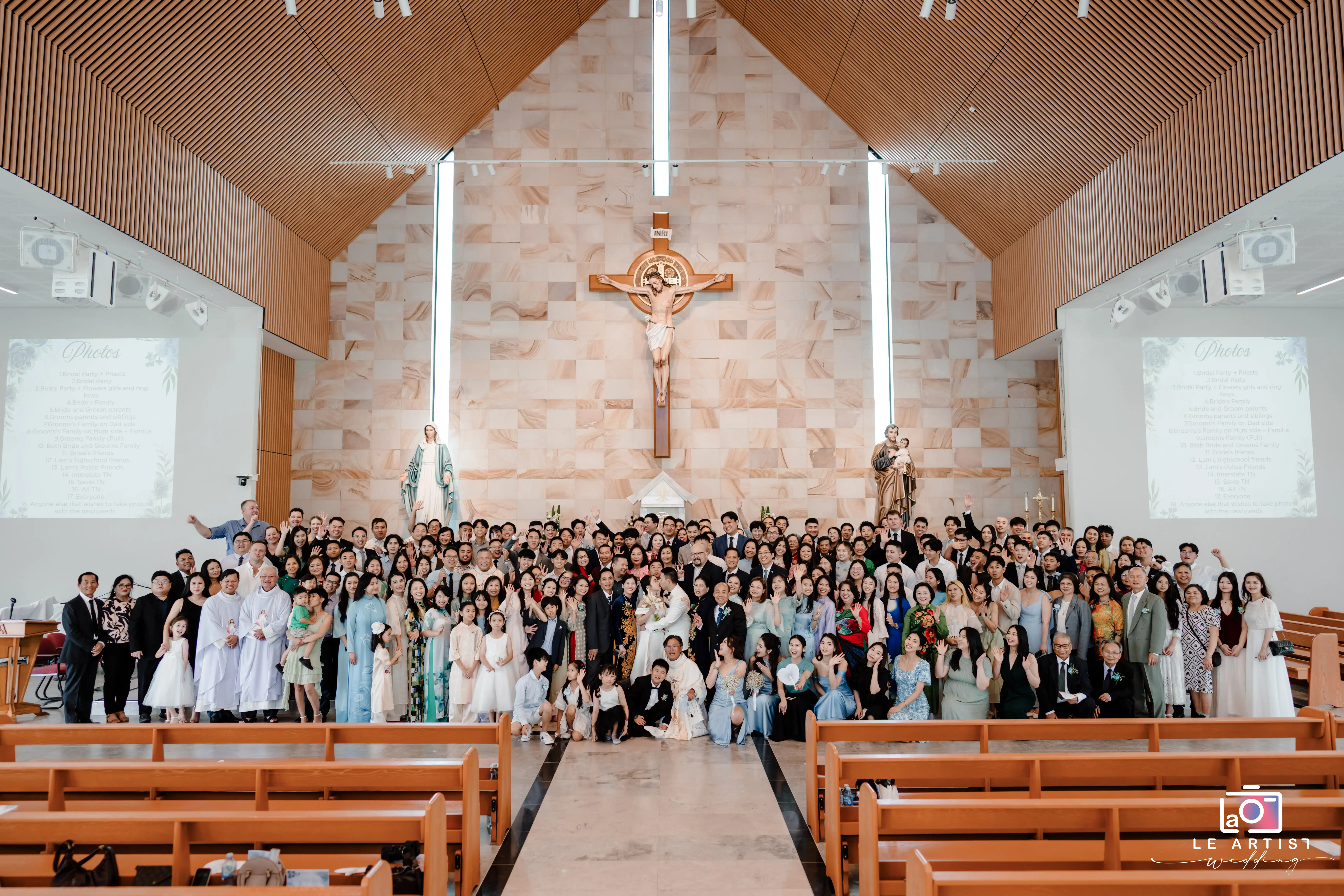 A joyful group photo in the church capturing the couple with their guests, celebrating the wedding ceremony. Le Artist Wedding
