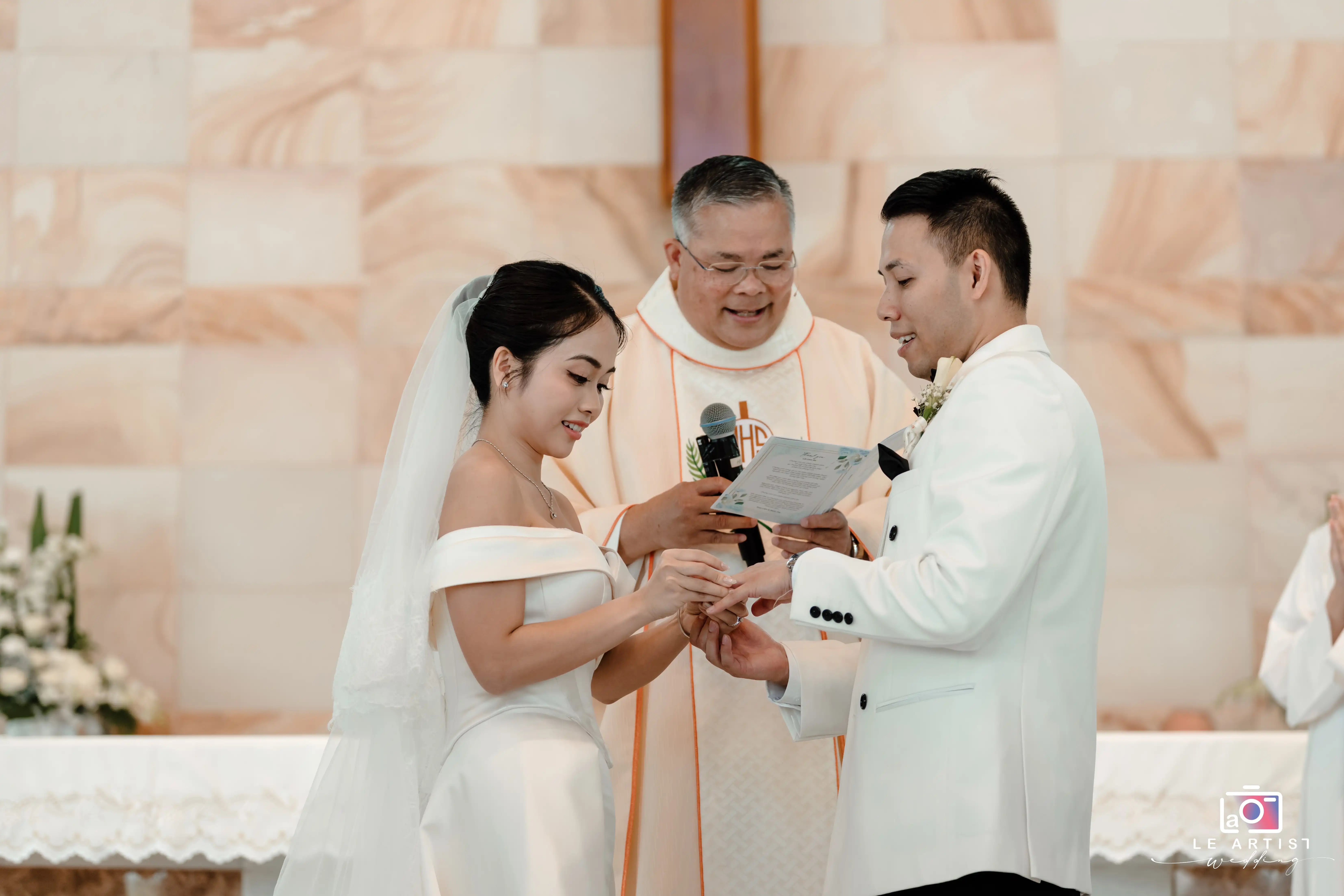 The couple exchanges rings during their wedding ceremony, a significant and heartfelt moment officiated by the celebrant. Le Artist Wedding