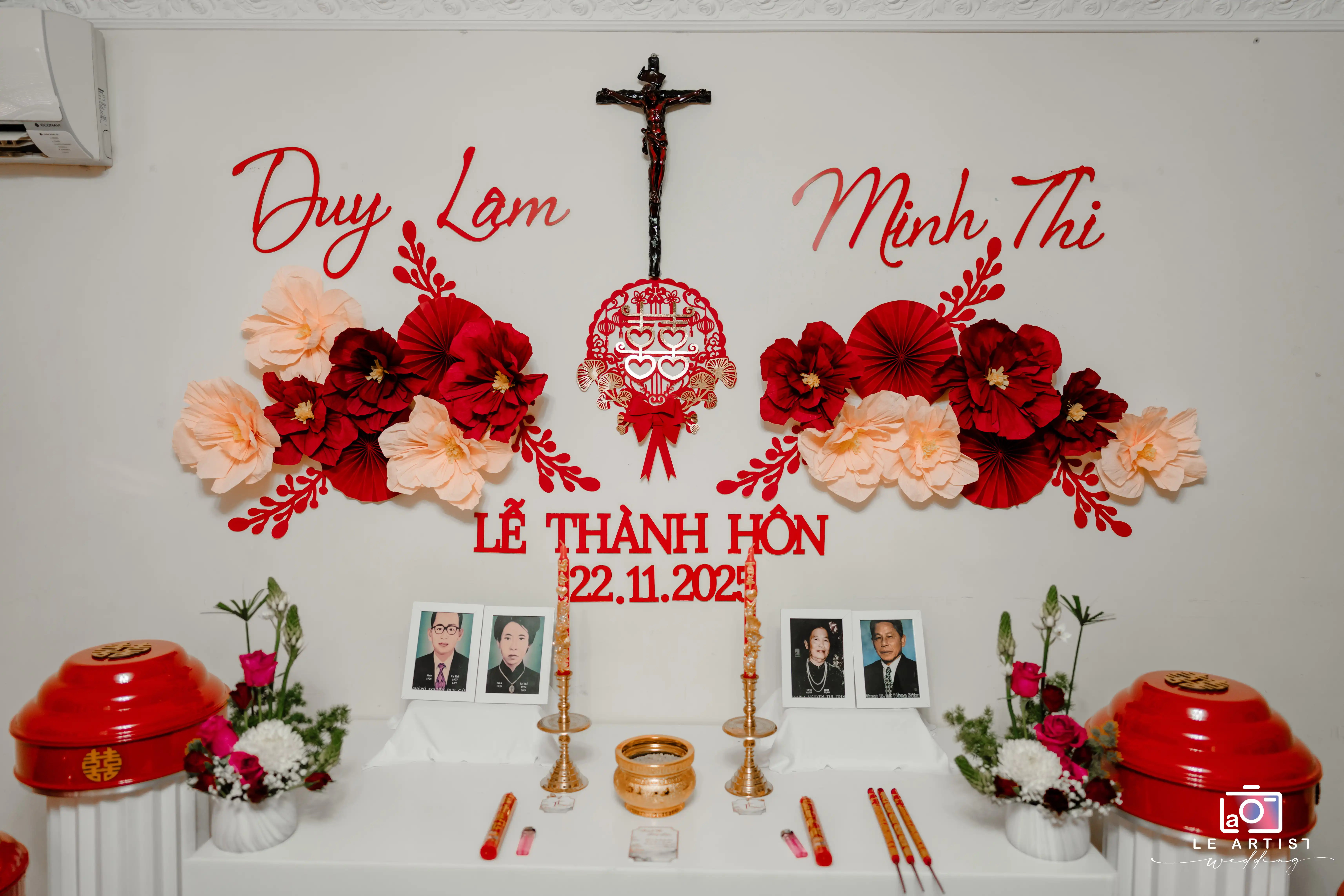 A traditional wedding altar setup featuring decorative flowers, family photos, and ceremonial items, symbolizing the union of Duy Lam and Minh Thi on November 22, 2023. Le Artist Wedding