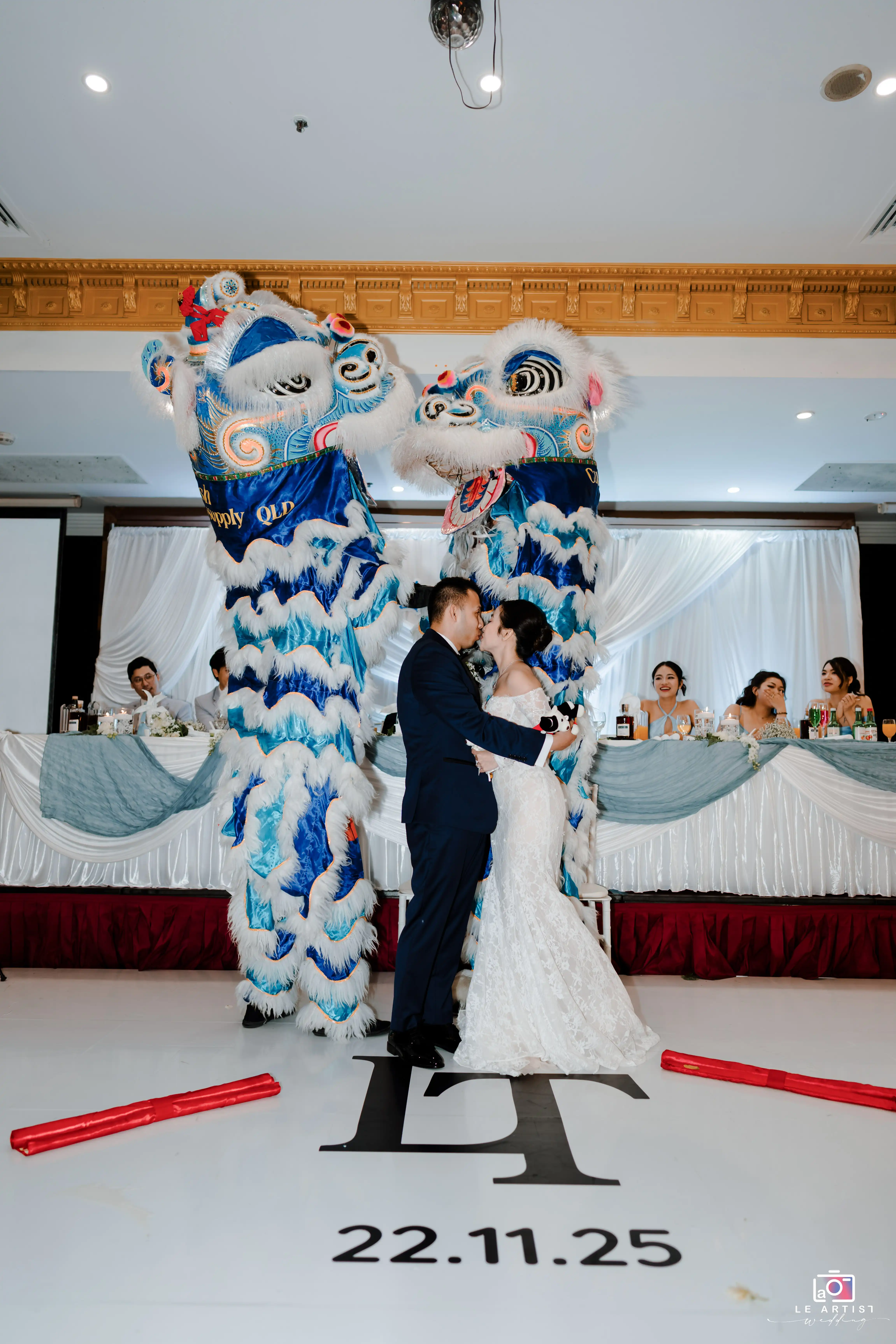 The couple shares a romantic moment on the dance floor, embraced by vibrant traditional lion dancers celebrating their union. Le Artist Wedding