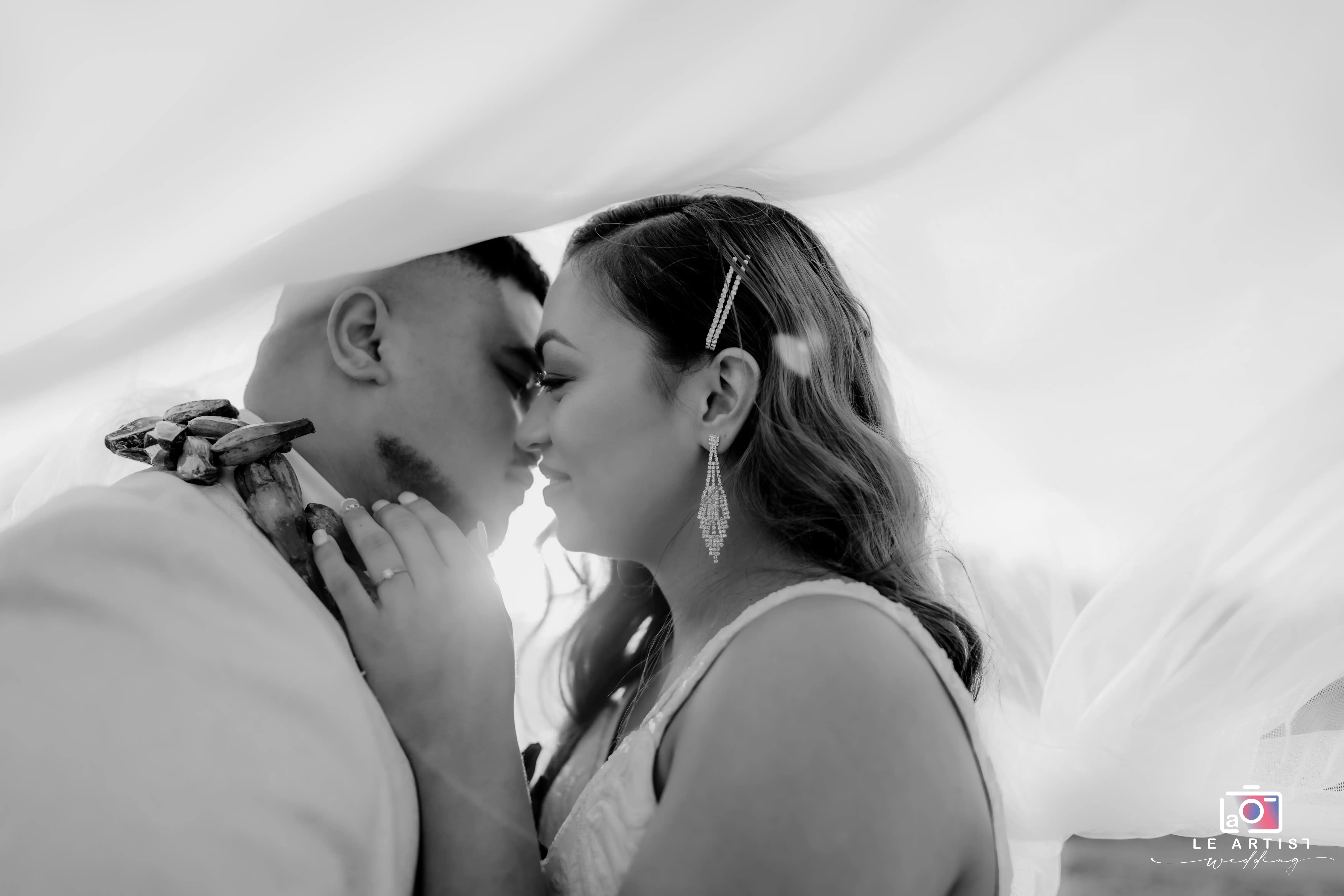 A tender moment captured during the bridal photoshoot, as the couple shares an intimate gaze beneath softly draped fabric. Le Artist Wedding