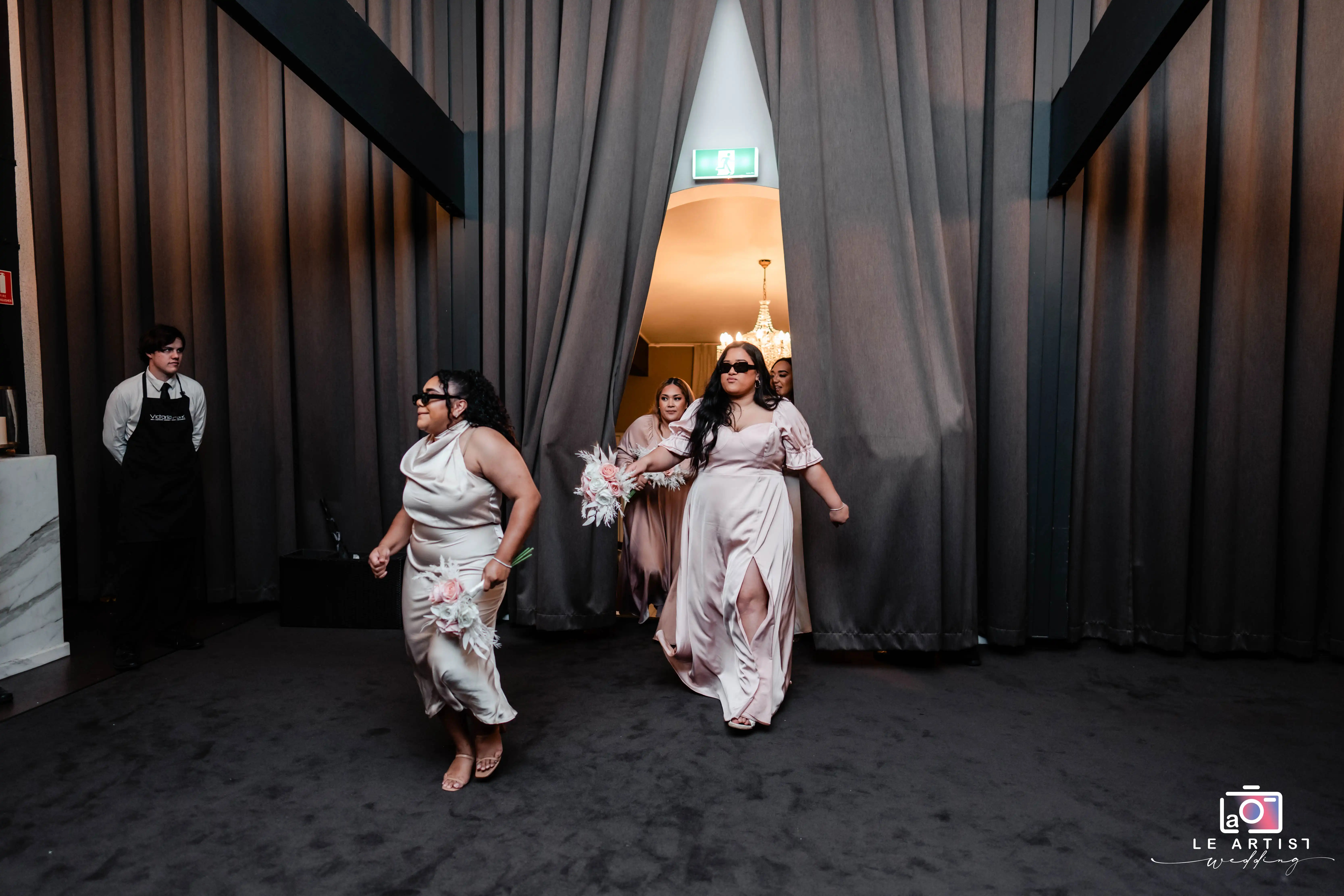 Bridesmaids make a playful entrance at the reception, setting a joyful tone for the celebration. Le Artist Wedding