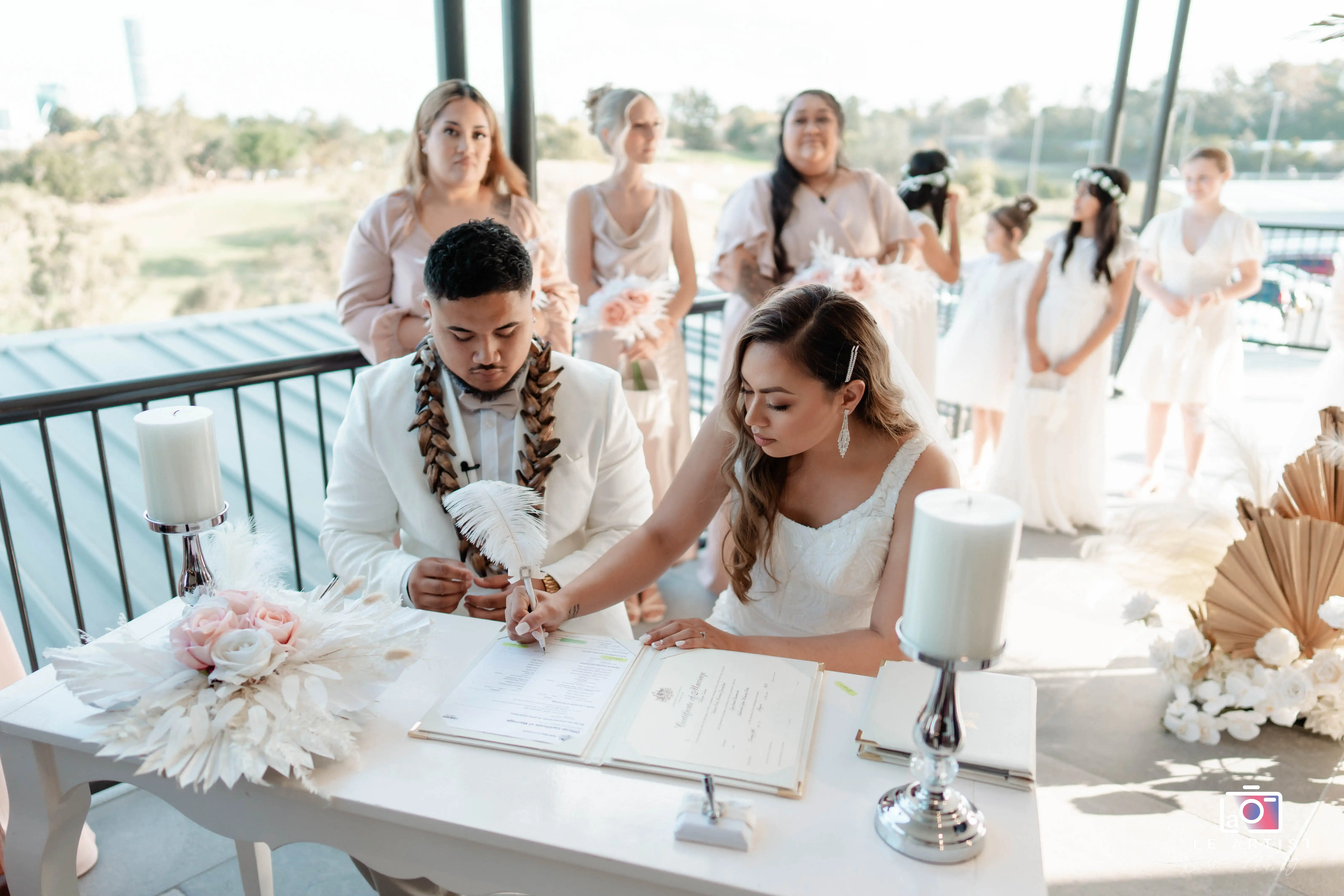 The couple signs the marriage certificate during the ceremony, witnessed by members of their bridal party. Le Artist Wedding