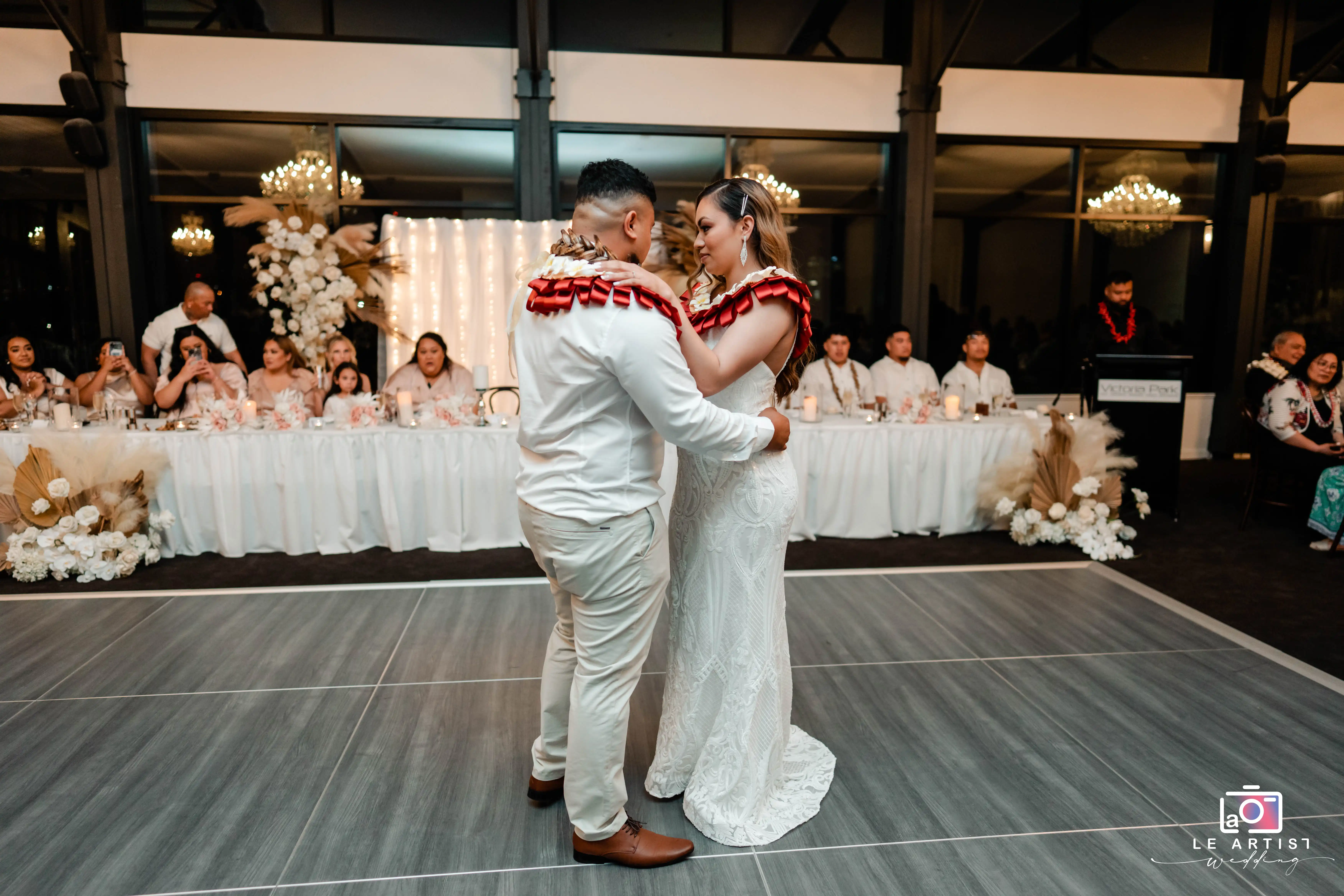 The couple shares a heartfelt first dance surrounded by their guests, marking a beautiful moment at the reception. Le Artist Wedding