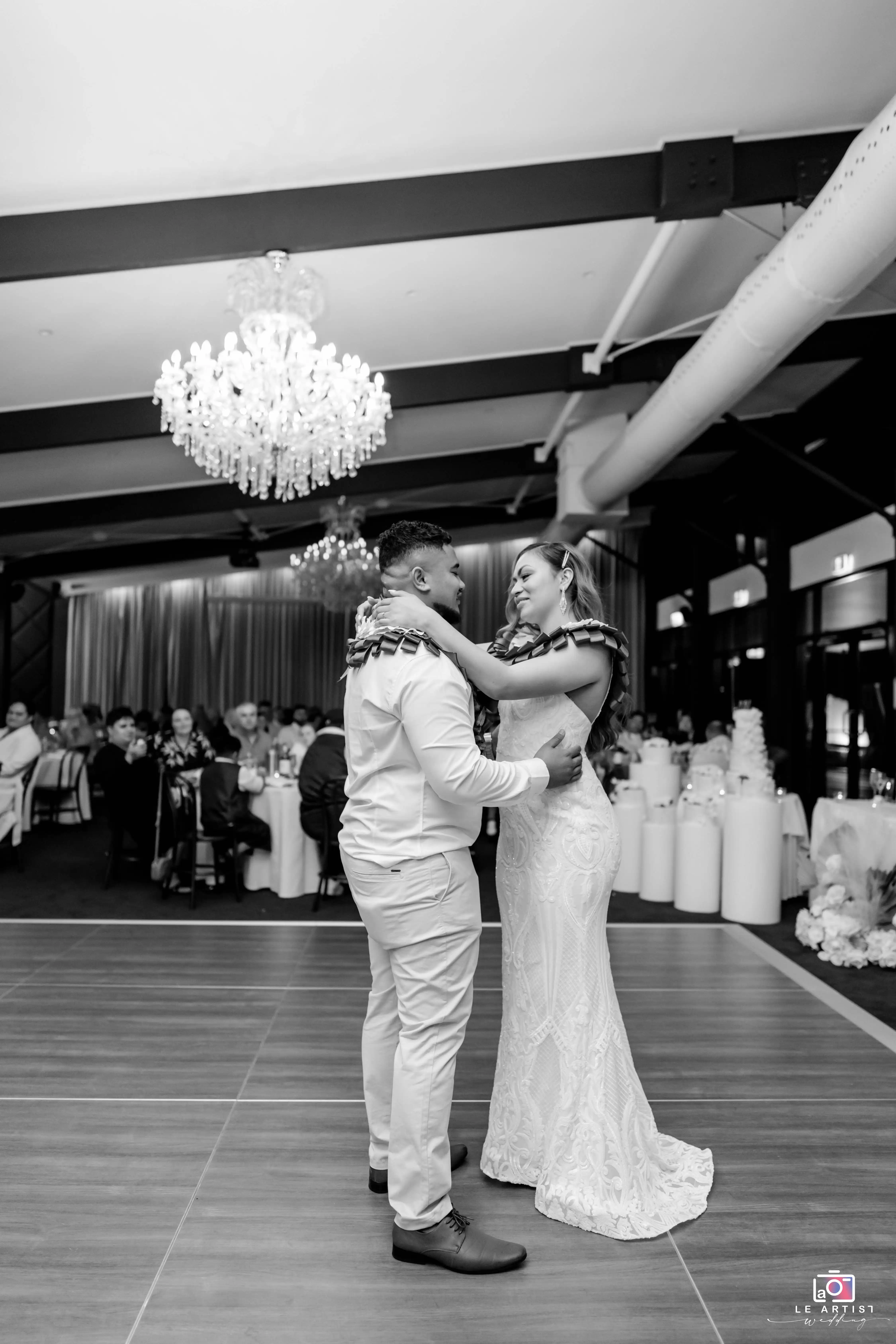 The couple shares a heartfelt dance under a sparkling chandelier during the reception. Le Artist Wedding