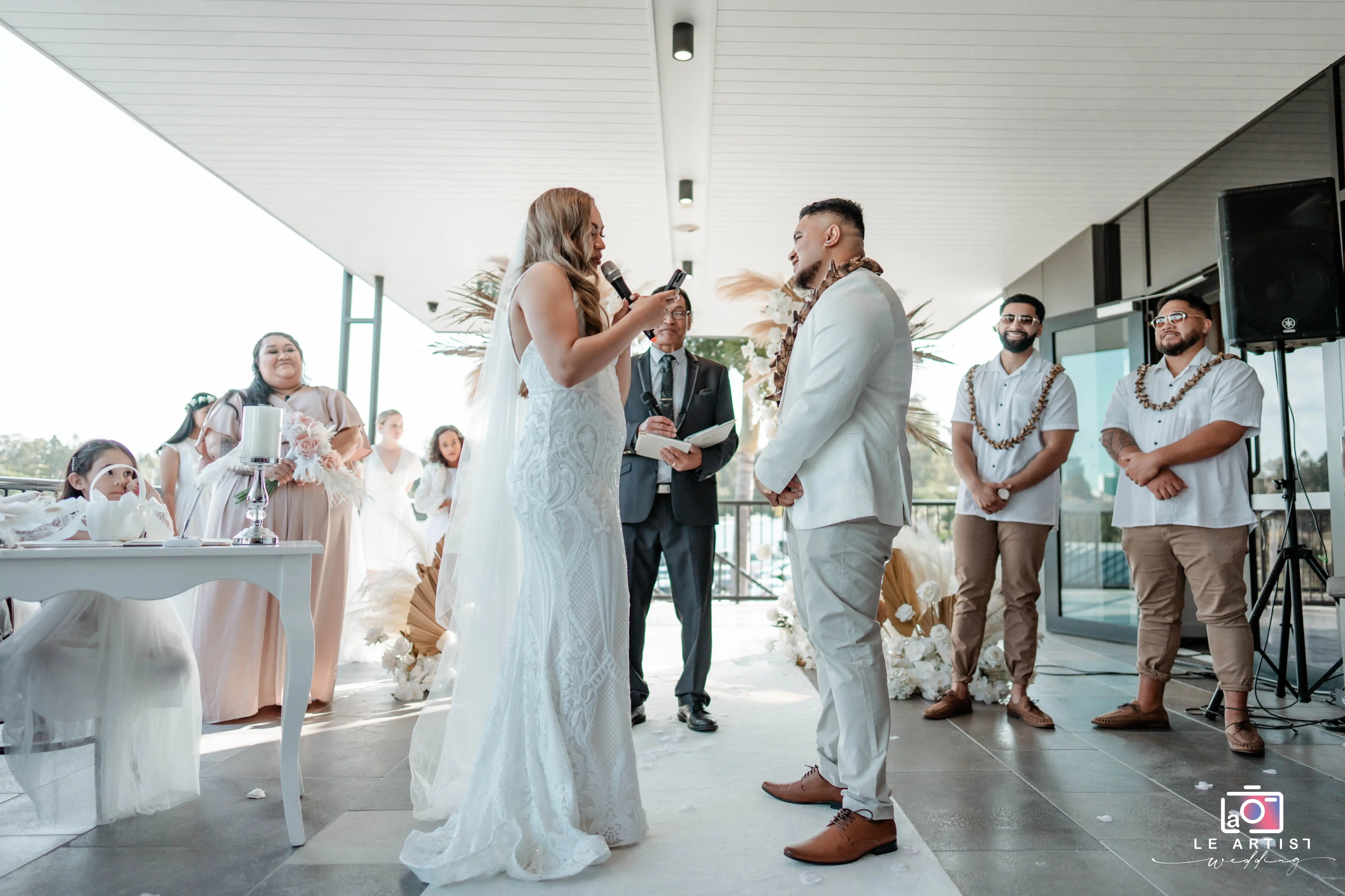 The couple shares heartfelt vows during their wedding ceremony, surrounded by their bridal party and officiant. Le Artist Wedding